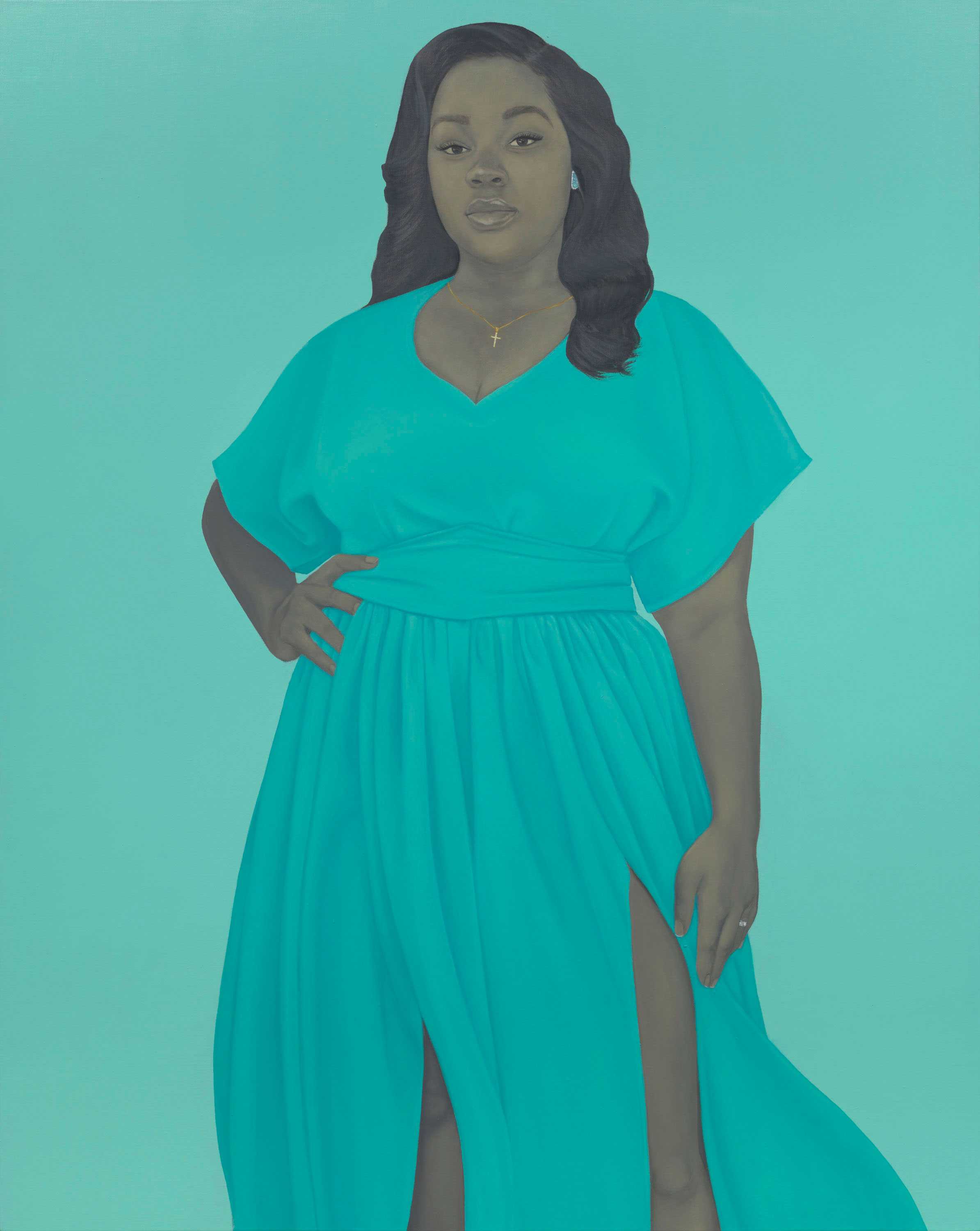 Breonna Taylor stands against a light blue-grey background in a flowing blue dress, a gold cross necklace and engagement ring.