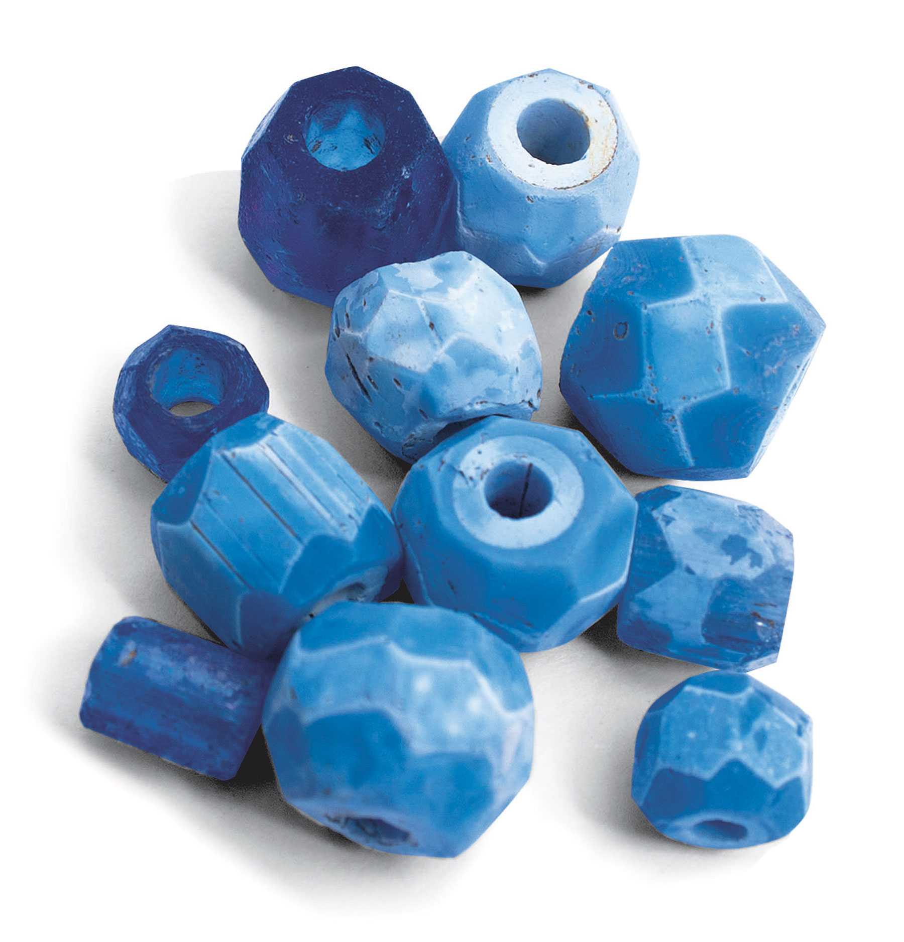 A close up view of indigo blue beads. While they vary in size and shape, they have a similar geometric pattern.