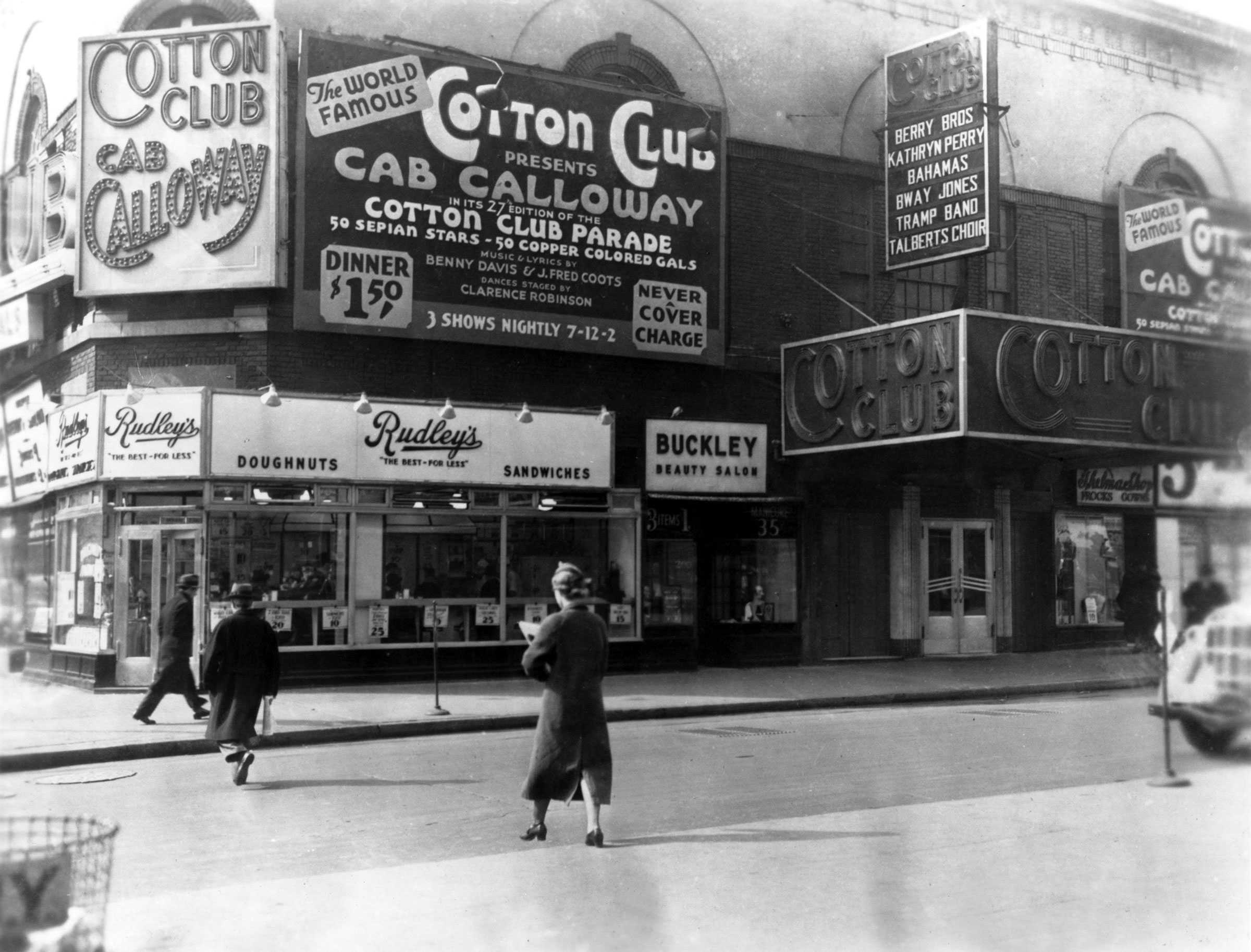 Black and white photograph of exterior of the "Cotton Club"  There are billboards advertising the club.