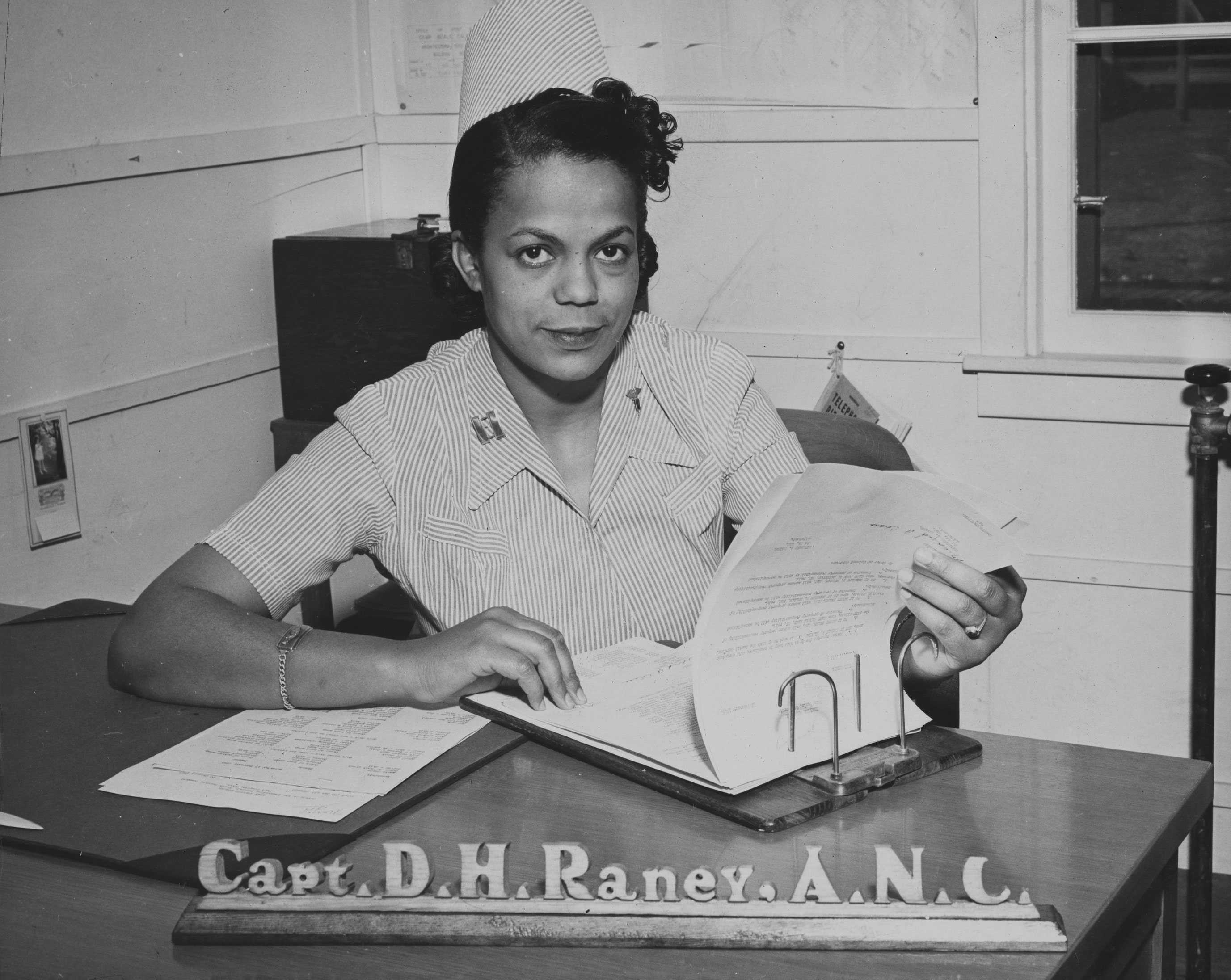 A picture of a nurse looking at a patient's chart from Major Della Hayden Raney's scrapbook.