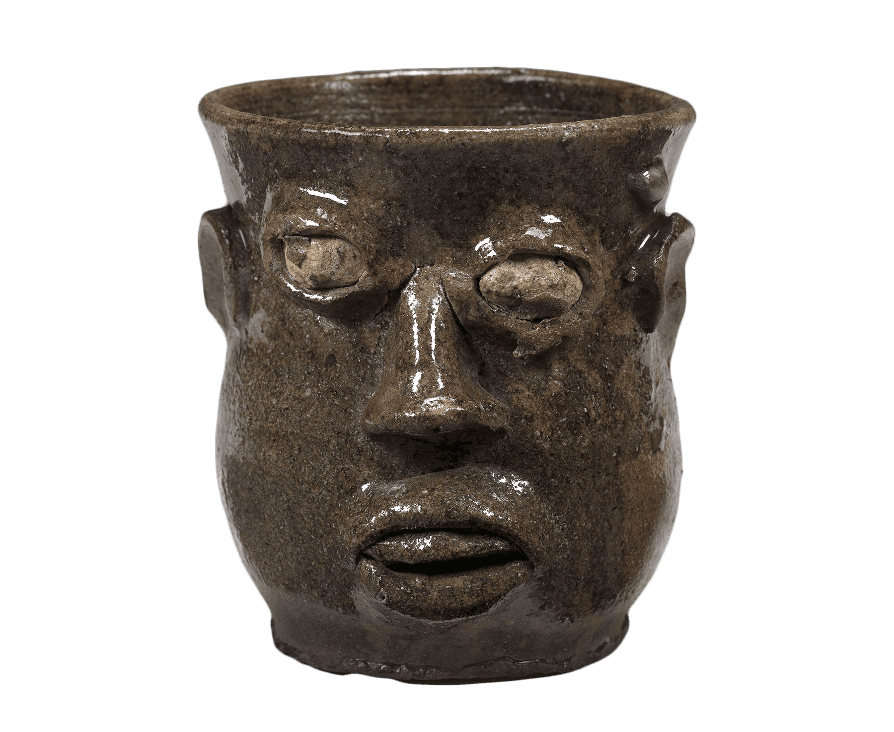 A brown cup with a carved face. The face includes eyes nose, mouth, and ears.