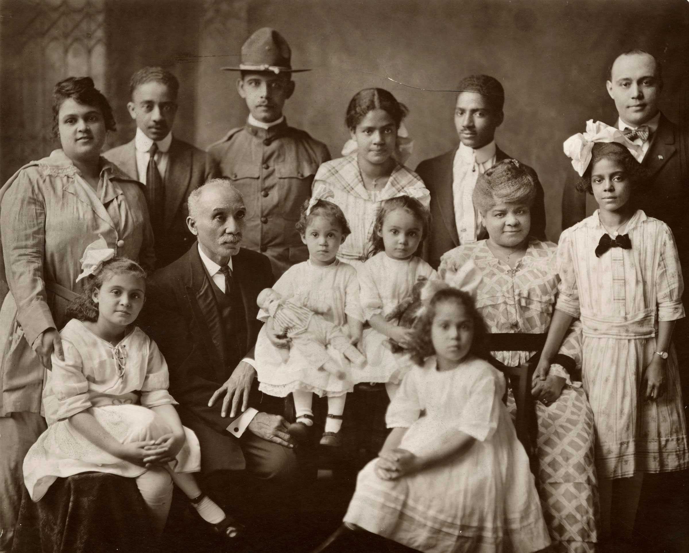 A sepia tone photograph of Ida B. Wells-Barnett and her family posed for a family photograph. There are children and grandchildren of many ages.