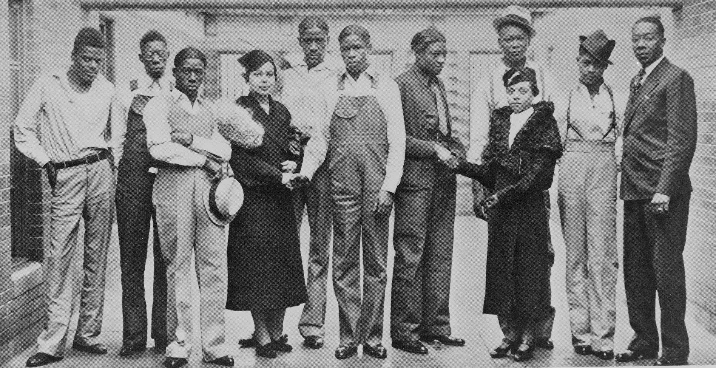 Black and white photograph showing a group of African American men posed with a smartly dressed woman.