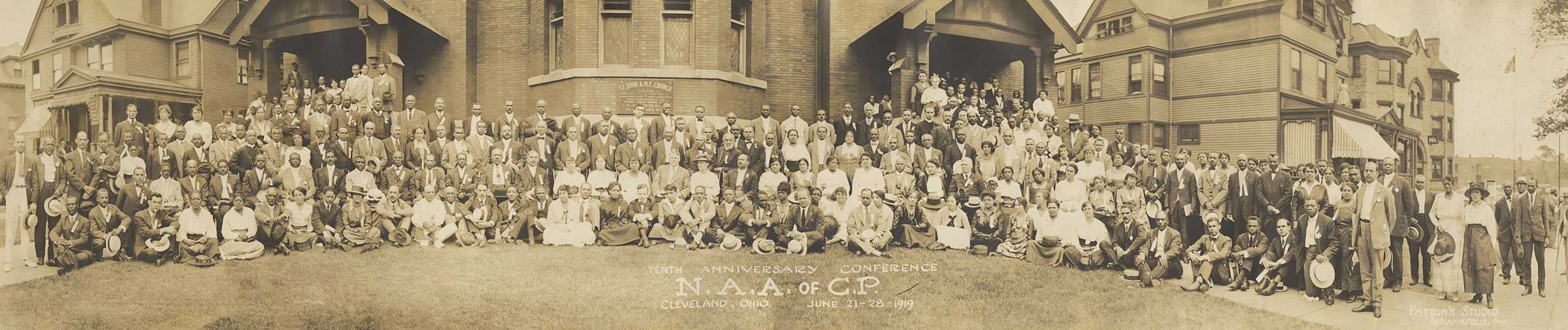 Panoramic photo showing a large group of people seated and standing in front of church building. The photo is embossed with "TENTH ANNIVERSARY CONFERENCE / N.A.A. OF C.P. / CLEVELAND, OHIO  JUNE 21-28-1919"