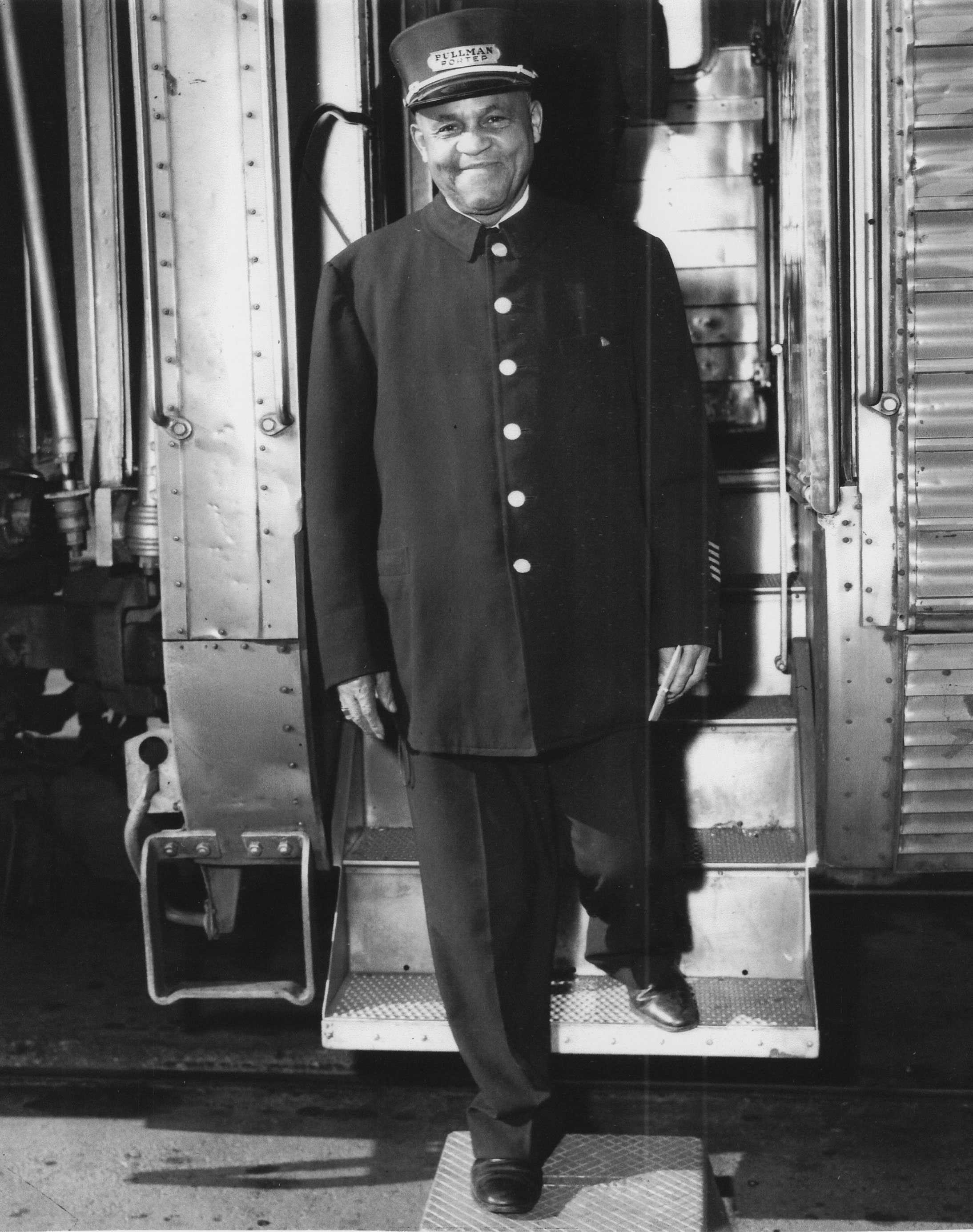 A black-and-white image of James Bryant in a Pullman Porter uniform standing on the steps of a Pullman railcar.