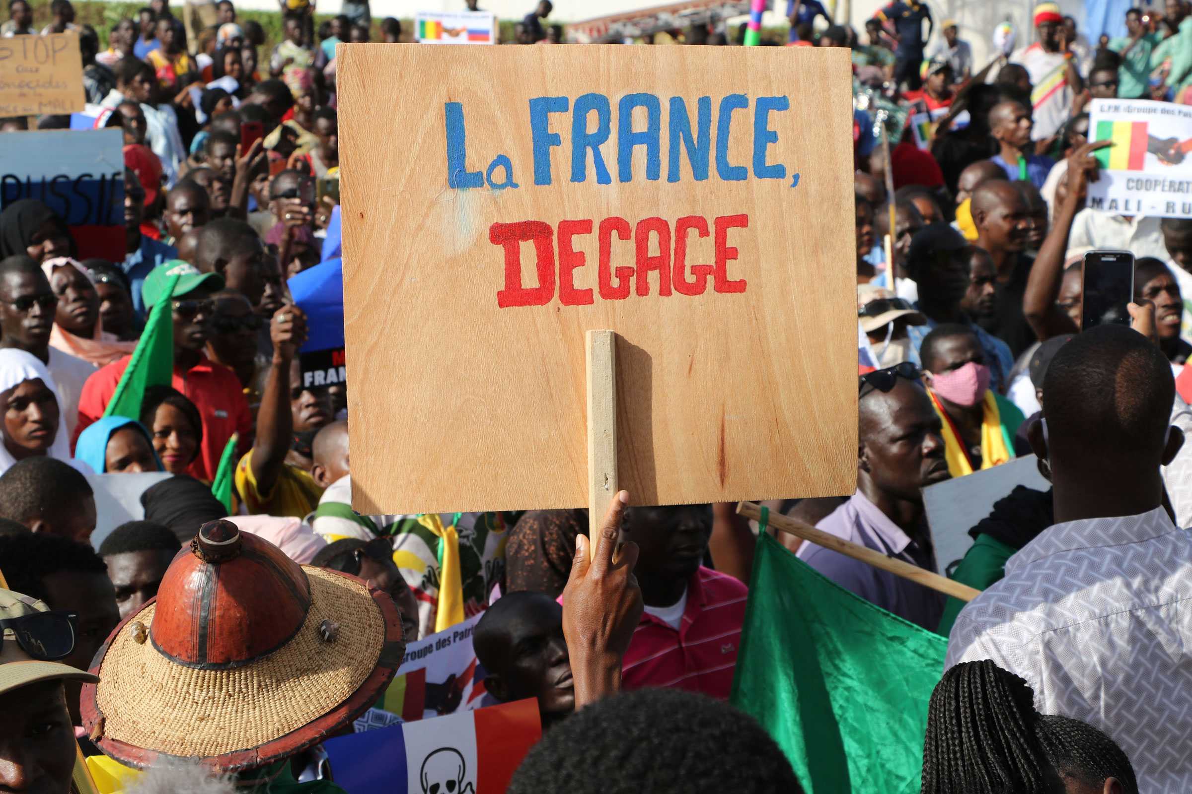 A plywood protest sign used during and anti-france protest. 'La France' is painted in blue and 'Degage' painted in red.