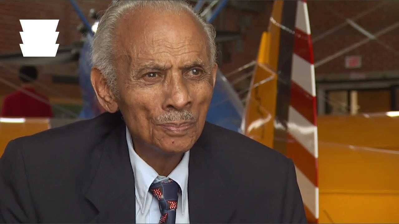 Older balding man sits in an hangar for an interview.