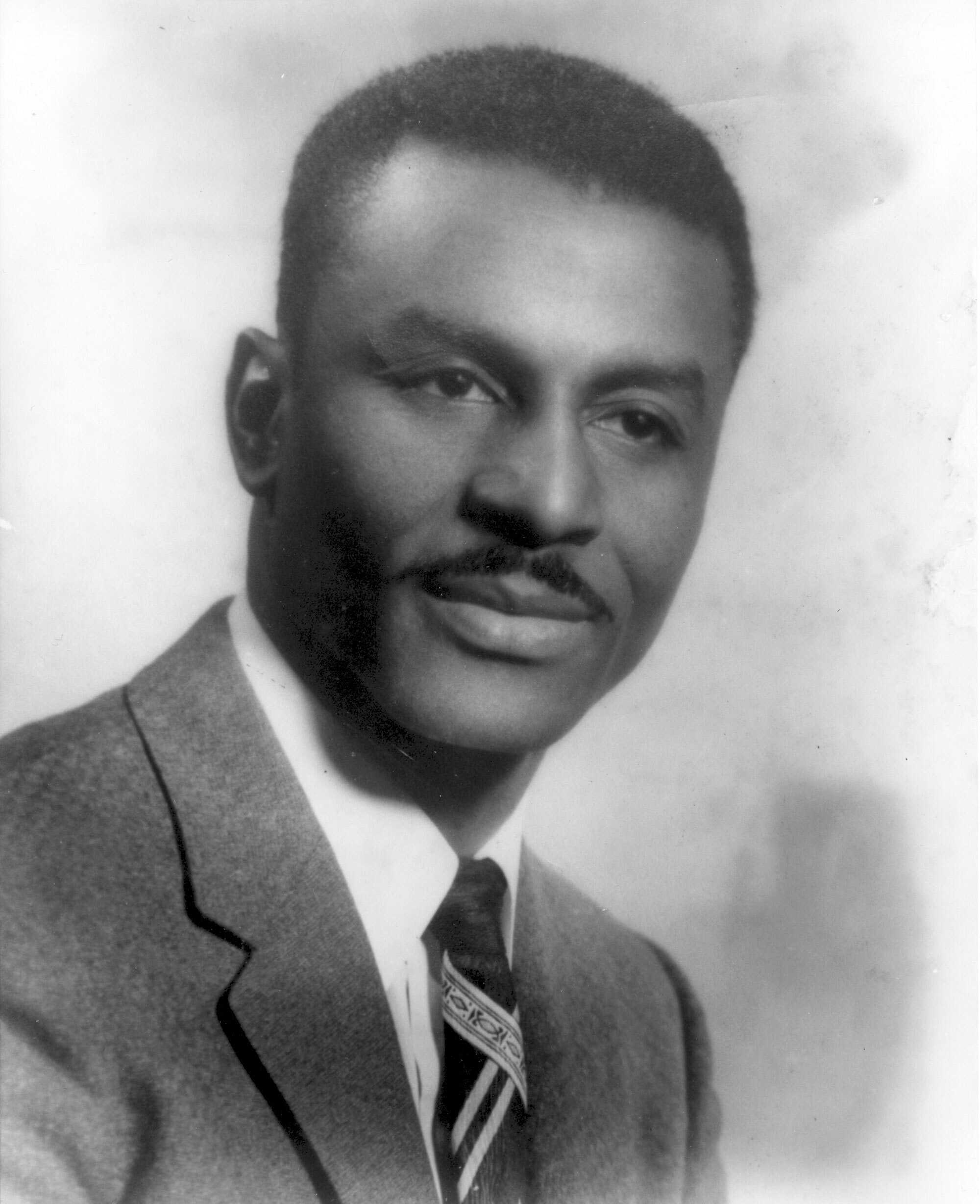 A black and white portrait of young Fred Shuttlesworth. He is dressed in a suit and tie.