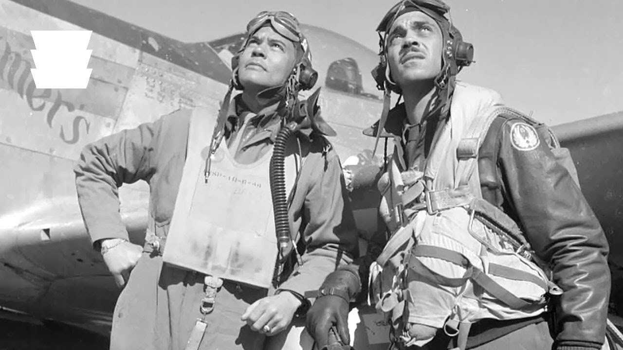 A black and white photo of two men standing in front of the an airplane.