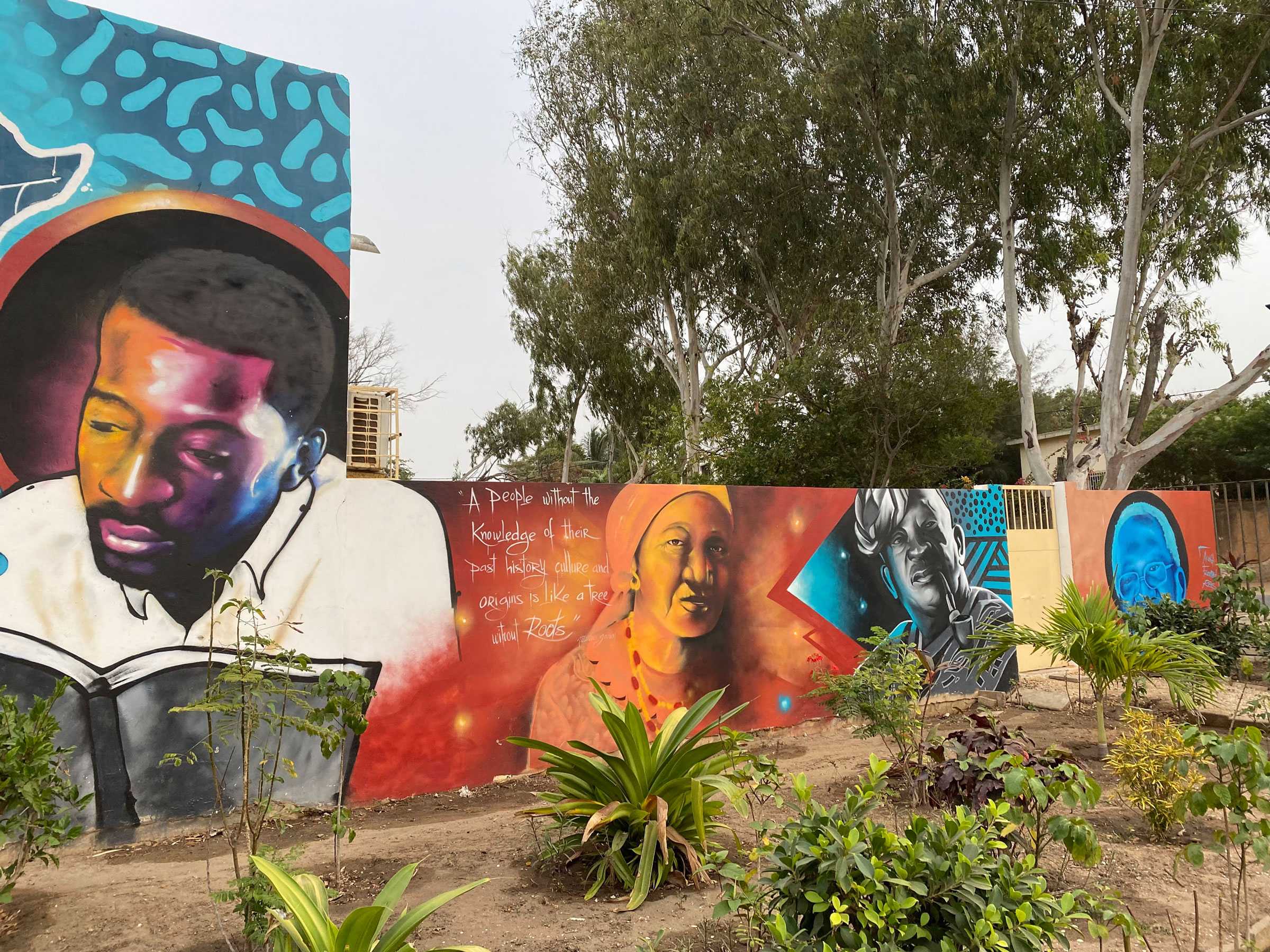 A brightly colored mural wall with a few faces, including Marème Diarra. A quote is to left of Marème Diarra.