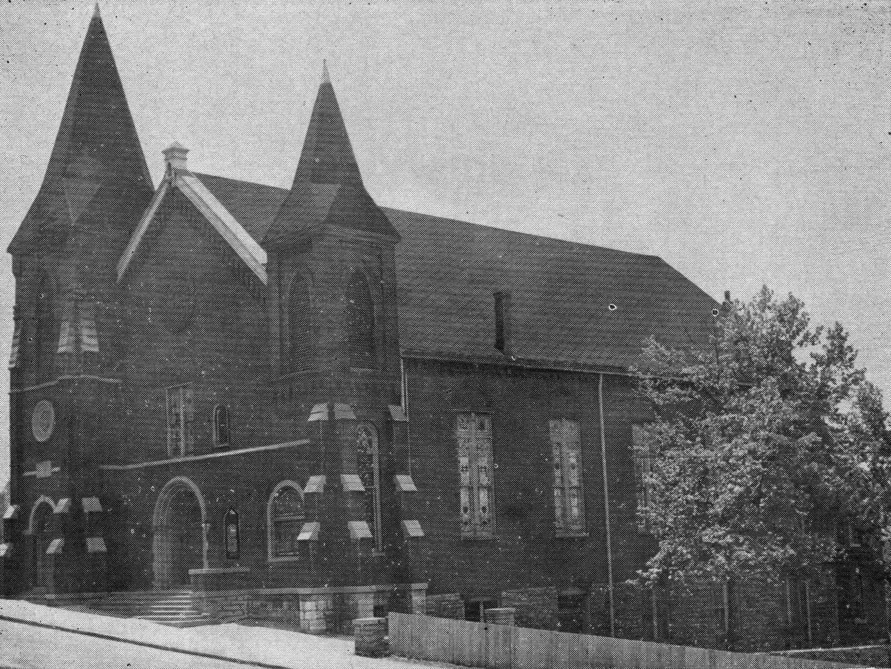 Black and white image of an unidentified church building with stained glass windows and two spires.