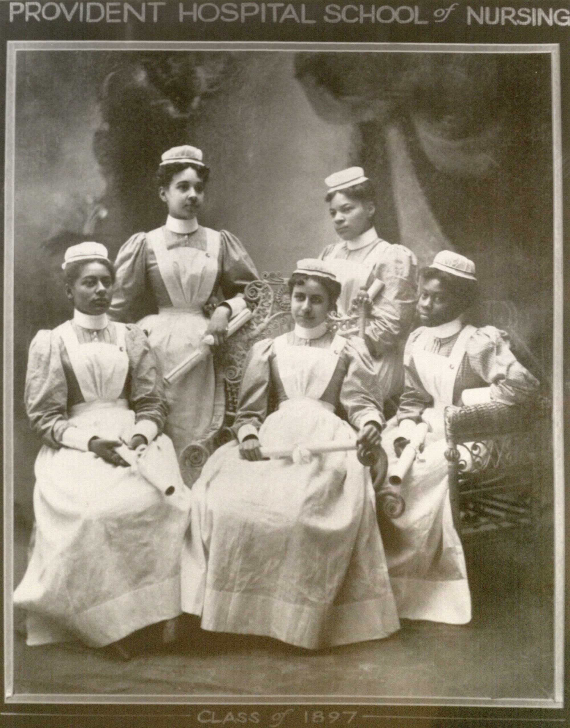 Black and white photograph of 5 young Black women dressed in nursing uniforms and holding diplomas.  The image has "PROVIDENT HOSPITAL SCHOOL OF NURSING" written on the top of the image and "CLASS OF 1897 / SARAH E. ADAMS / GRACE CRAIG / CORA ANDERSON / VIOLA SIMONS/ JULIA SNELL" below the image.