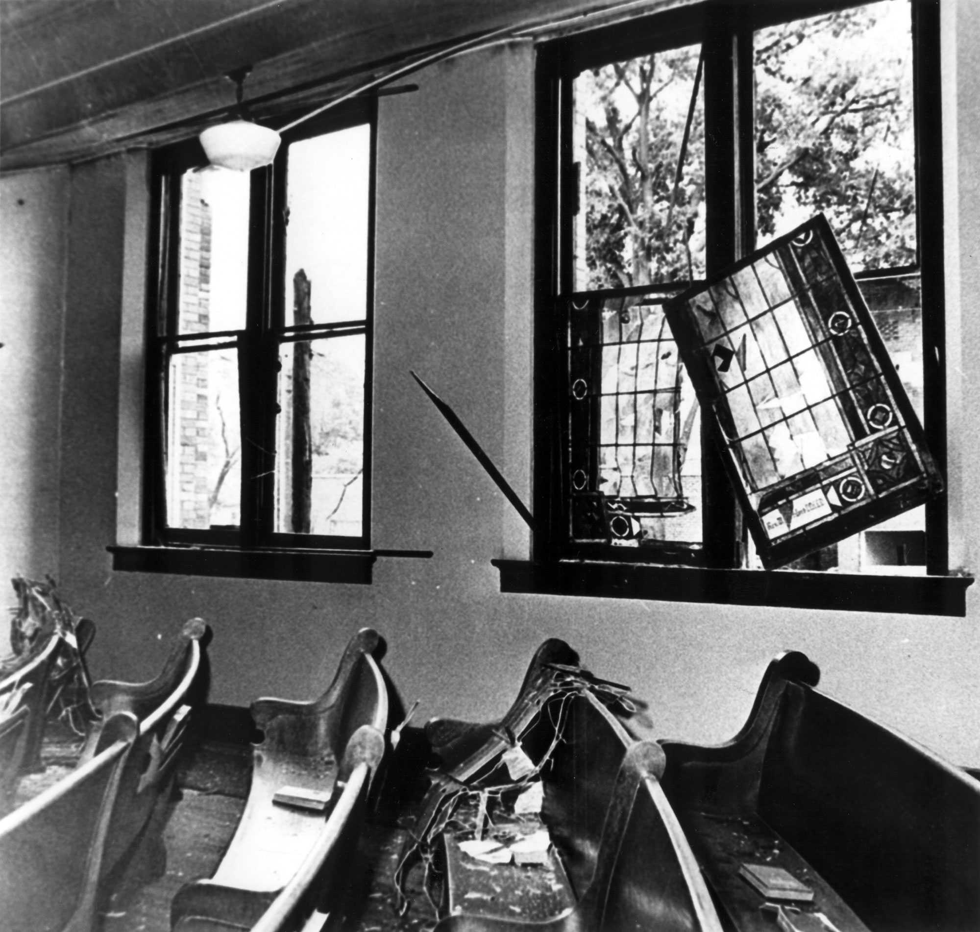 A photograph of the Sixteenth Street Baptist Church's nave after the bombing. Windows are broken and hang askew.