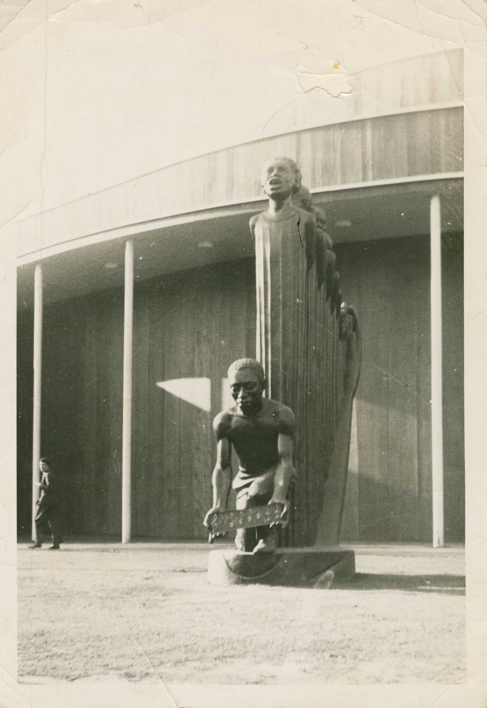 Black and white photograph of Augusta Savage's 16-foot tall sculpture, "Lift Every Voice and Sing," with the world fair building behind it.