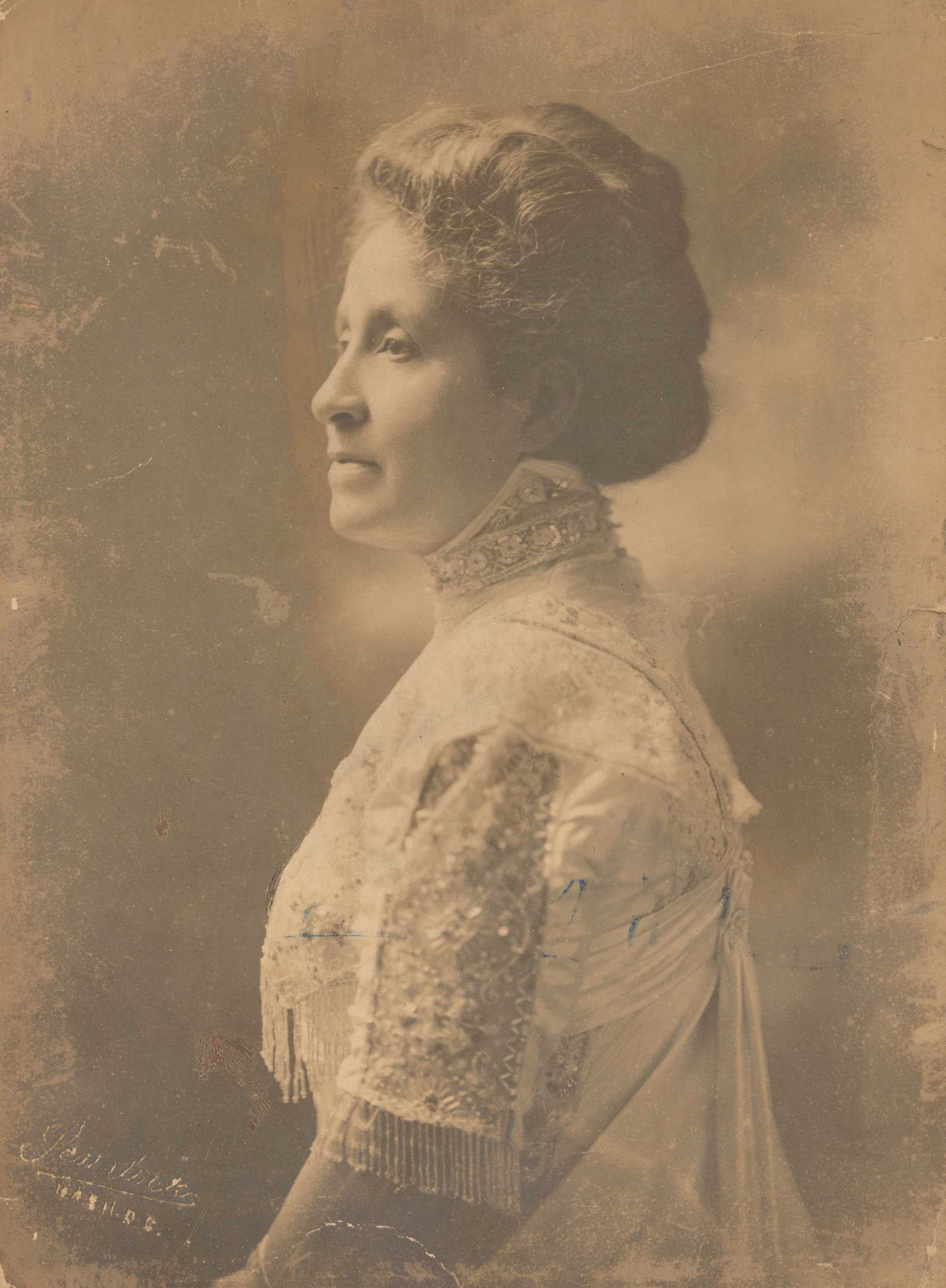 A black and white photograph of Mary Church Terrell seated in profile from the waist up, wearing a light-colored beaded and fringed evening dress.