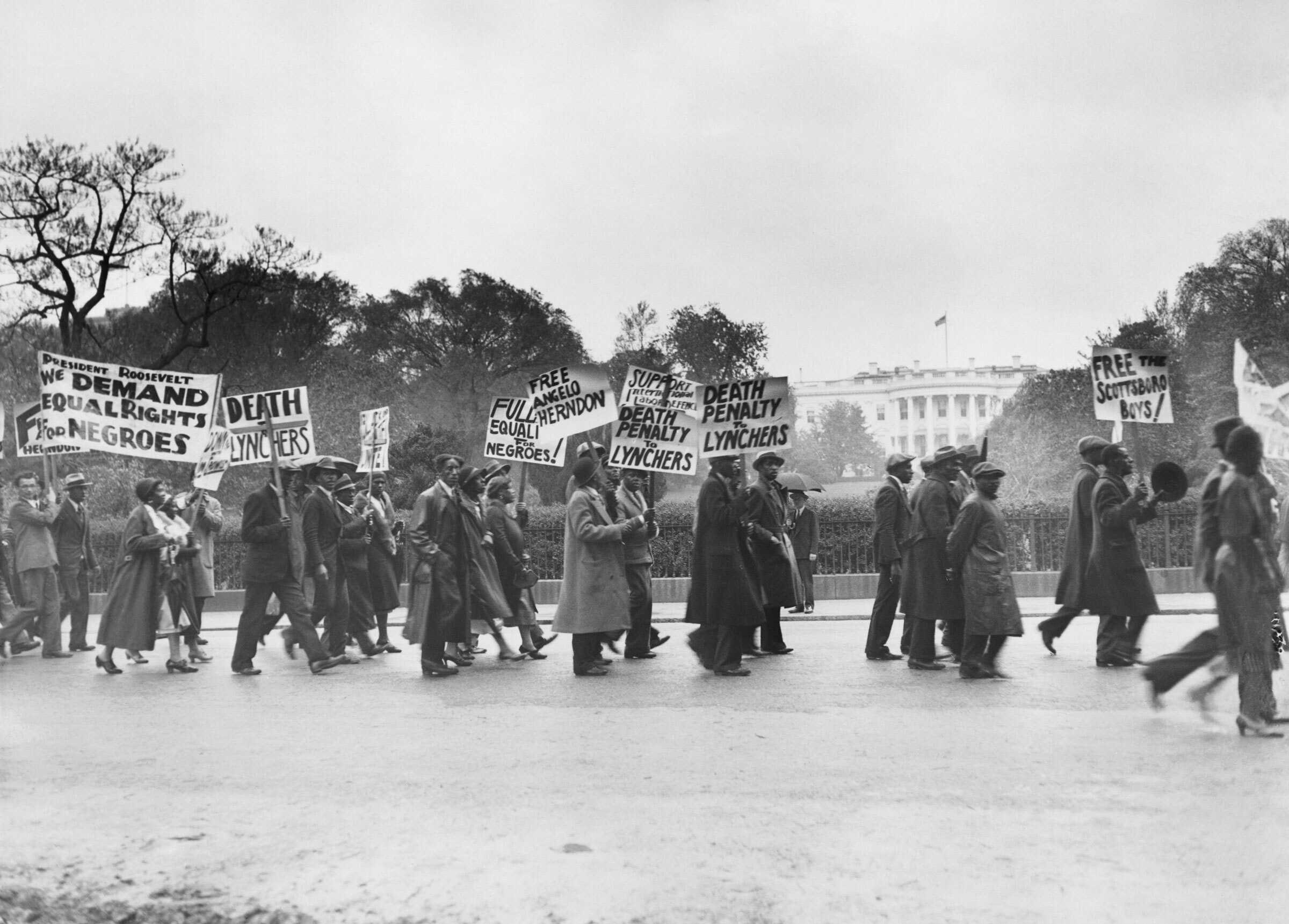 Black and white photograph of protesters marching in front of White House.