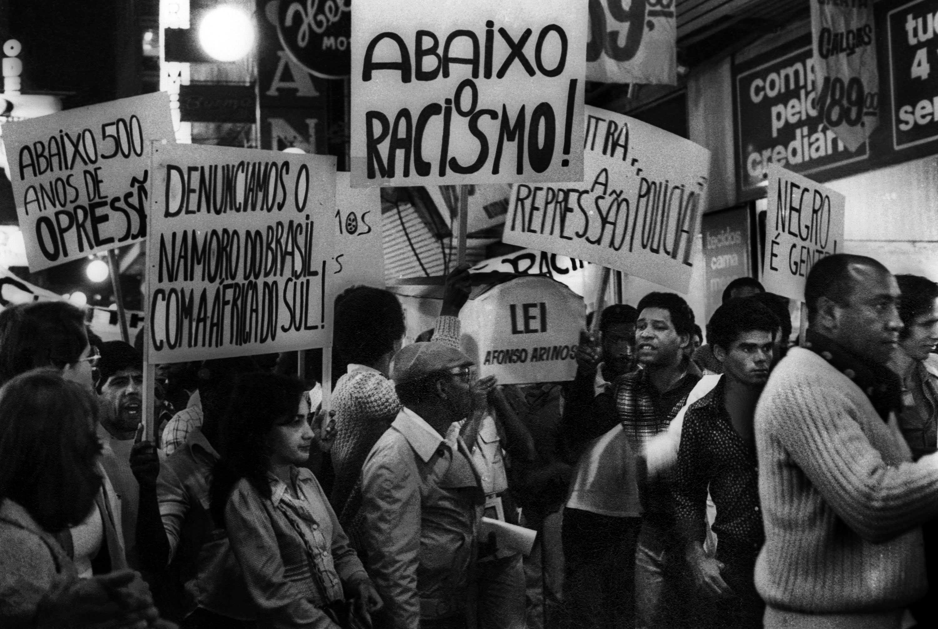 A black and white photograph of protestors in São Paulo, Brazil protesting racism with signs in Portuguese.