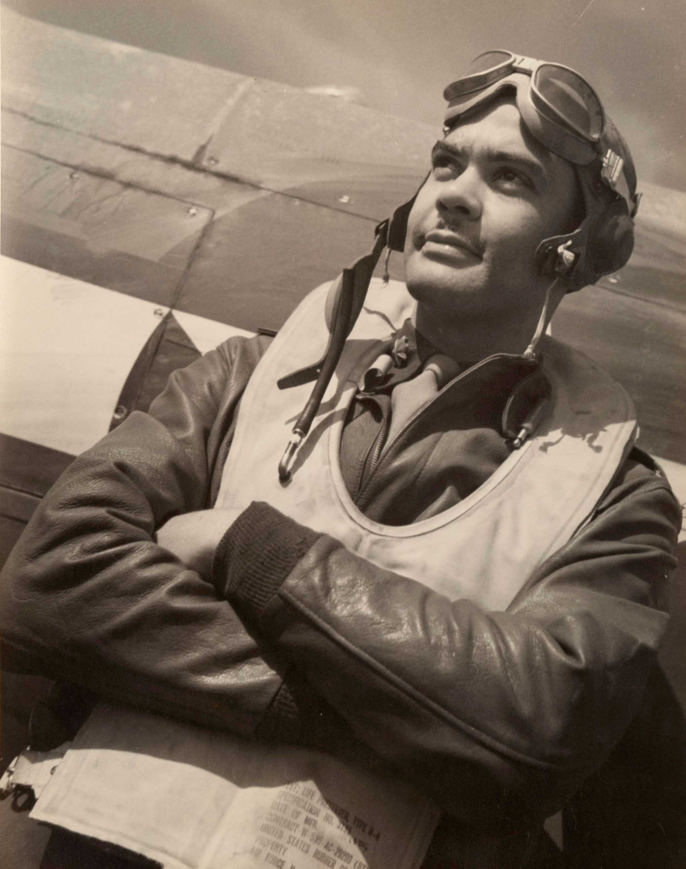 A black and white photo of Tuskegee Airmen Benjamin O. Davis, Jr. standing in flight gear in front of a plane.