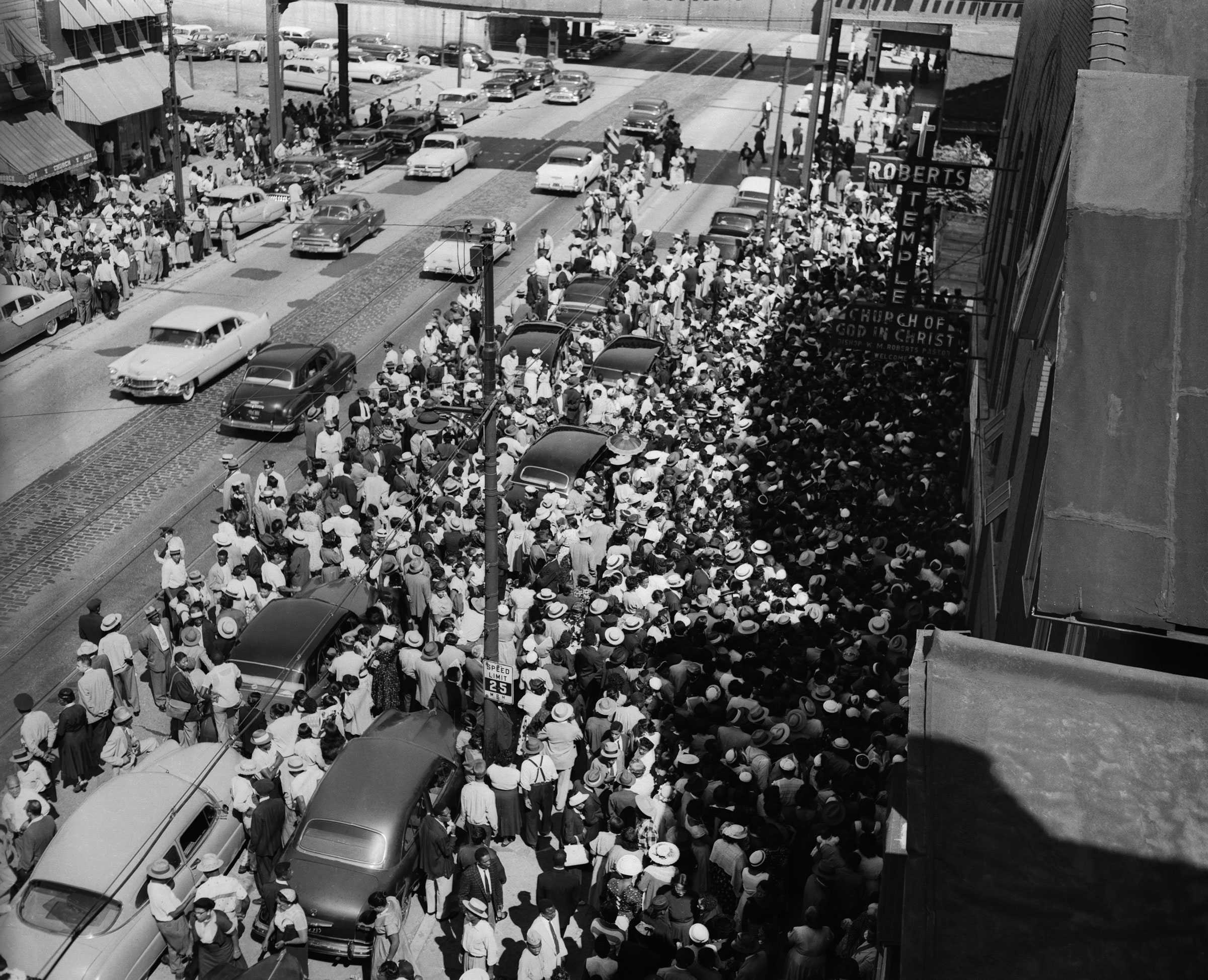 A black and white photograph of large crowd of mourners outside the entrance to Roberts Temple Church of God in Christ.