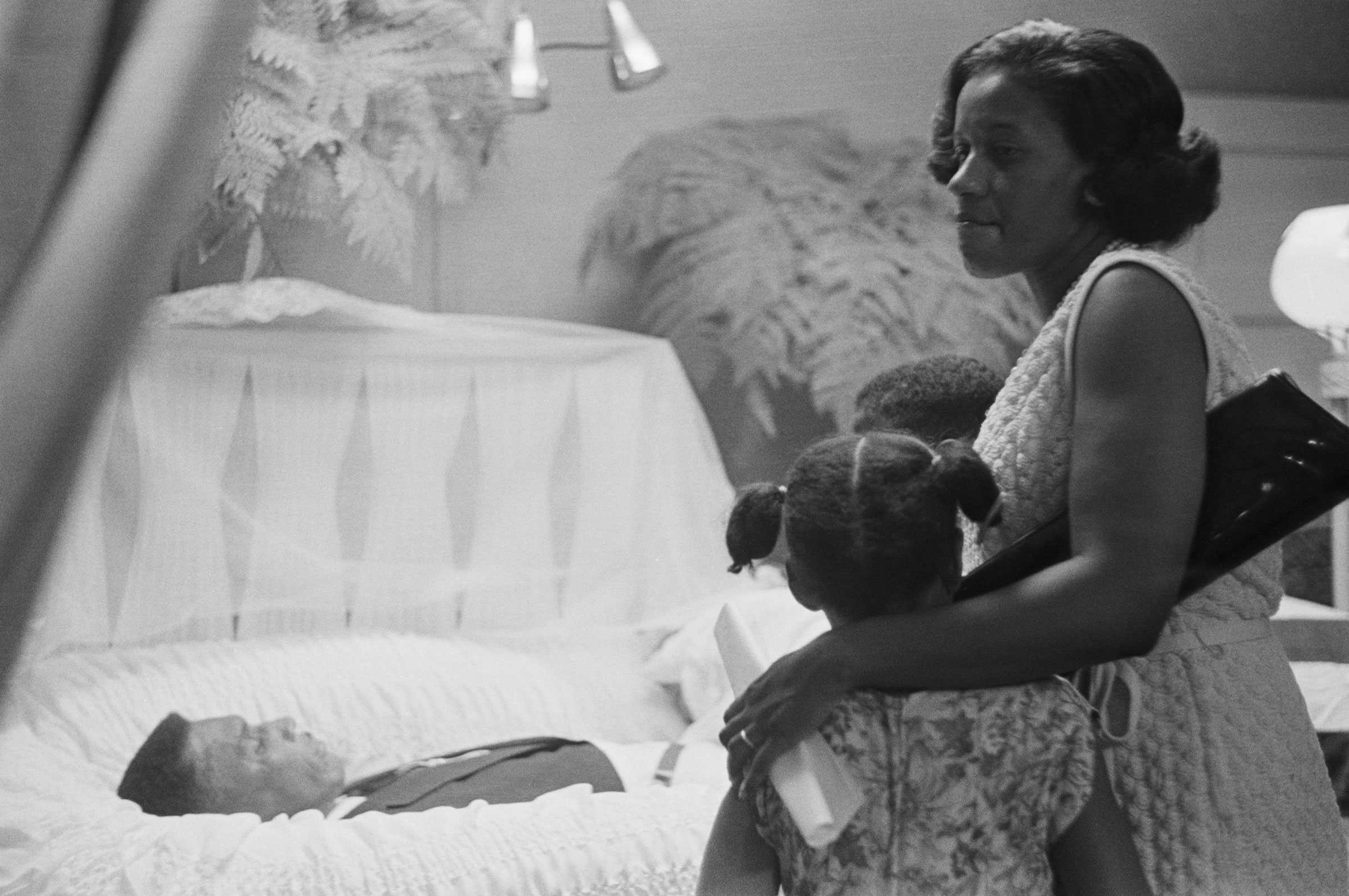 Myrlie Evers holds her children closely as they view Medgar Evers in his casket in a funeral home.