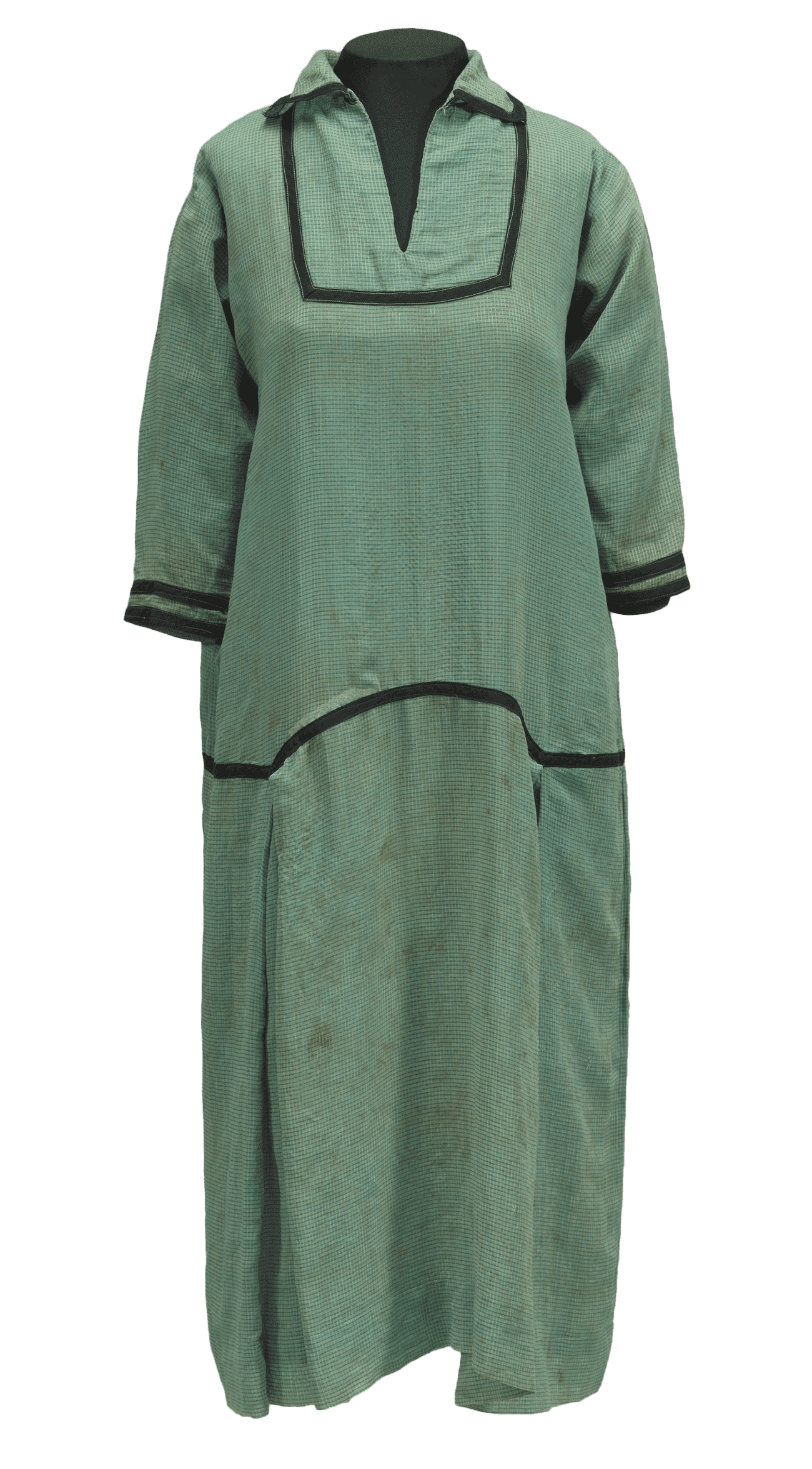 A green and cream checked A-line dress with black trimmings. It has a split-front neckline, fitted sleeves, a drop waist, and a pleated skirt.