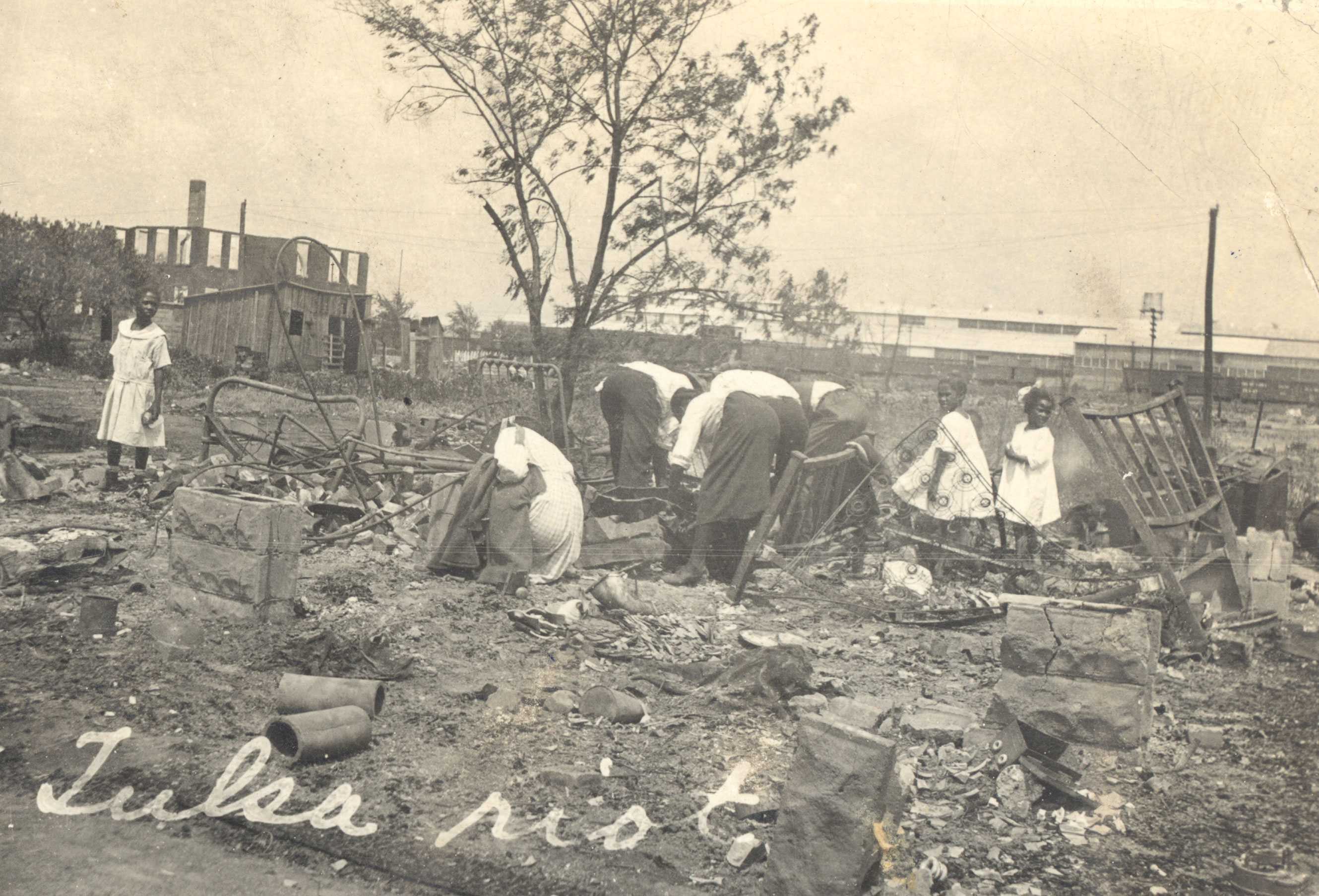 Black and white photograph of people sifting through rubble.