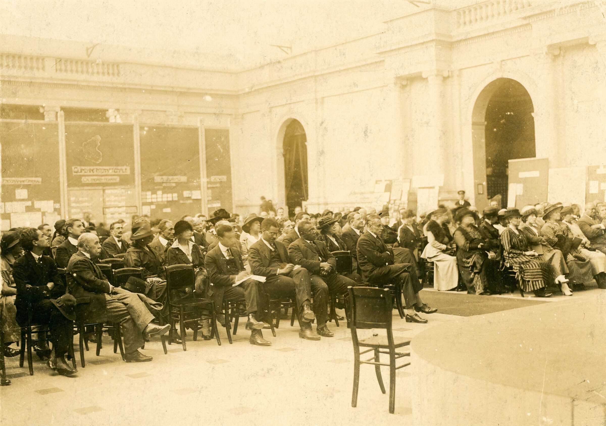 A sepia tone photograph of Pan-African Congress in Belgium in 1921. The crowd sits in a large hall facing the front of the room.