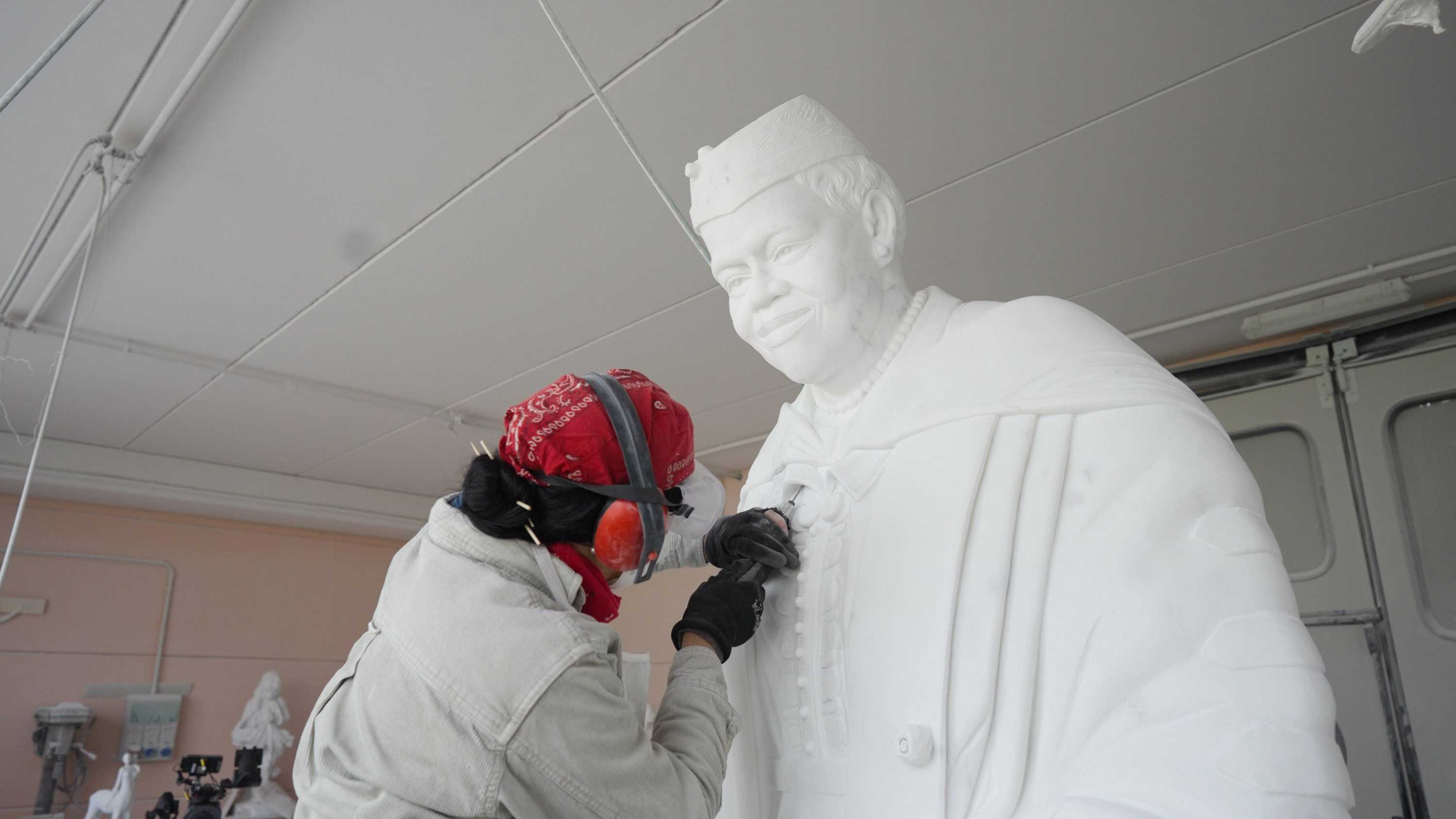 Color photograph of artist working on carving marble statue.