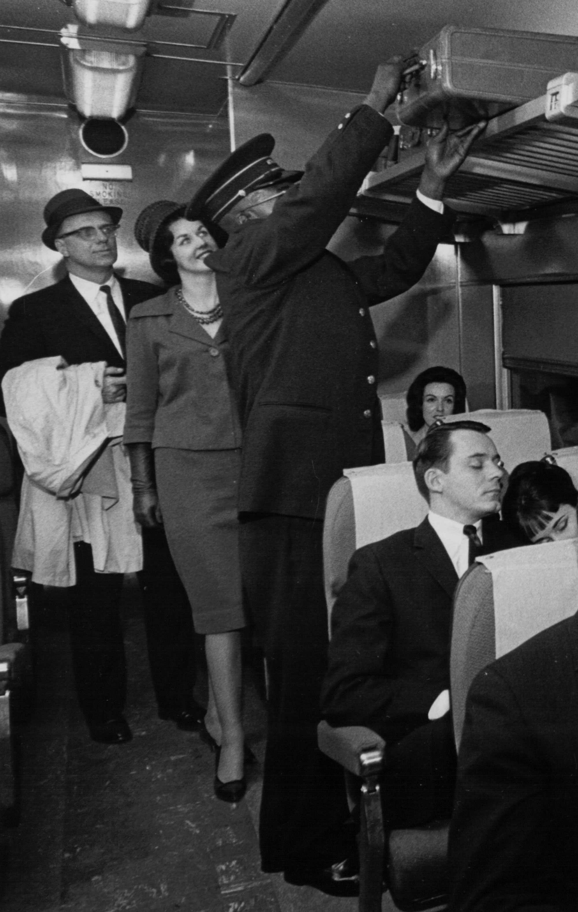 Black and White photograph of black train porter assisting passengers with their luggage.