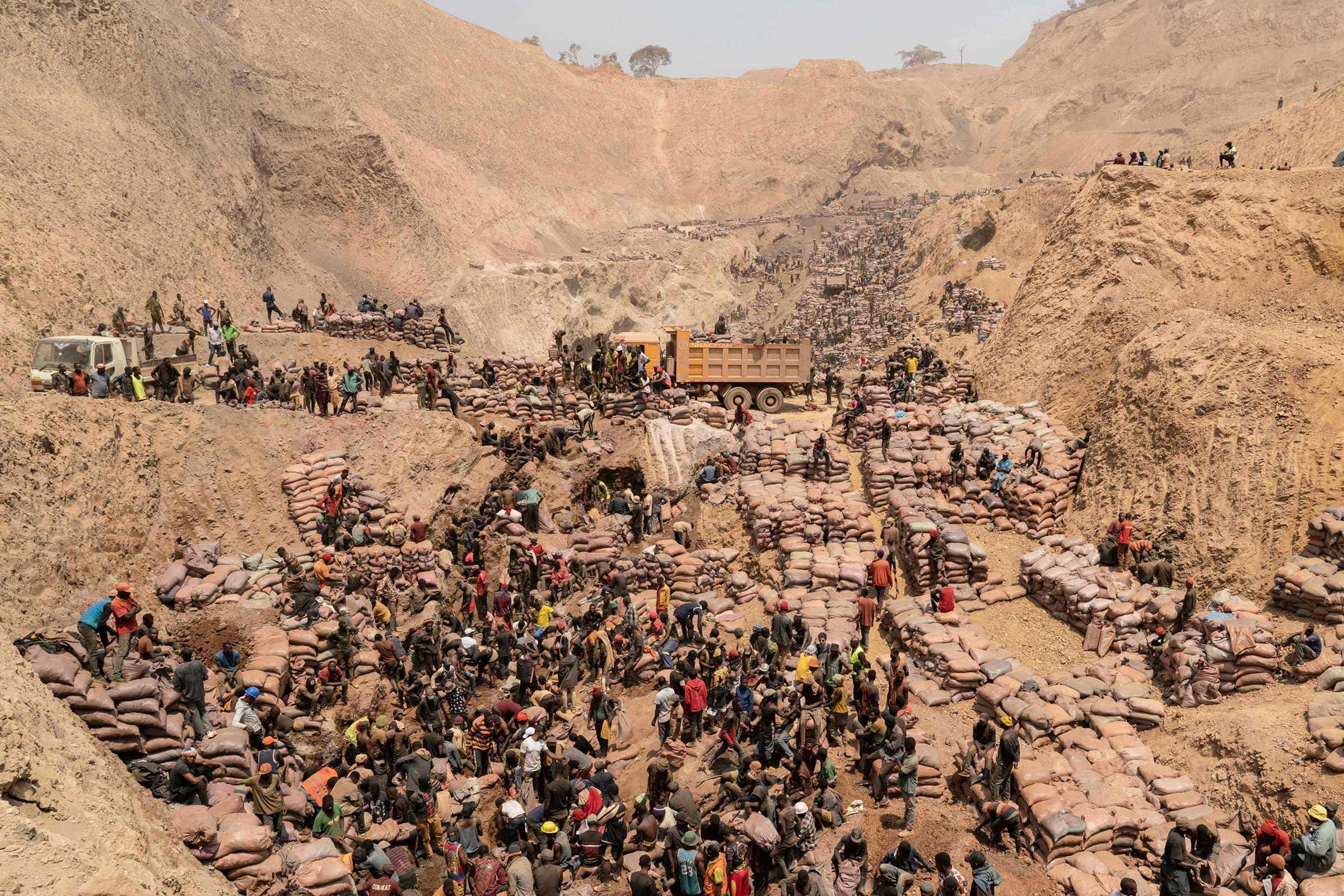 A high angle view of a dirt mine as miners work and organize bags of colbalt in the Democratic Republic of the Congo.