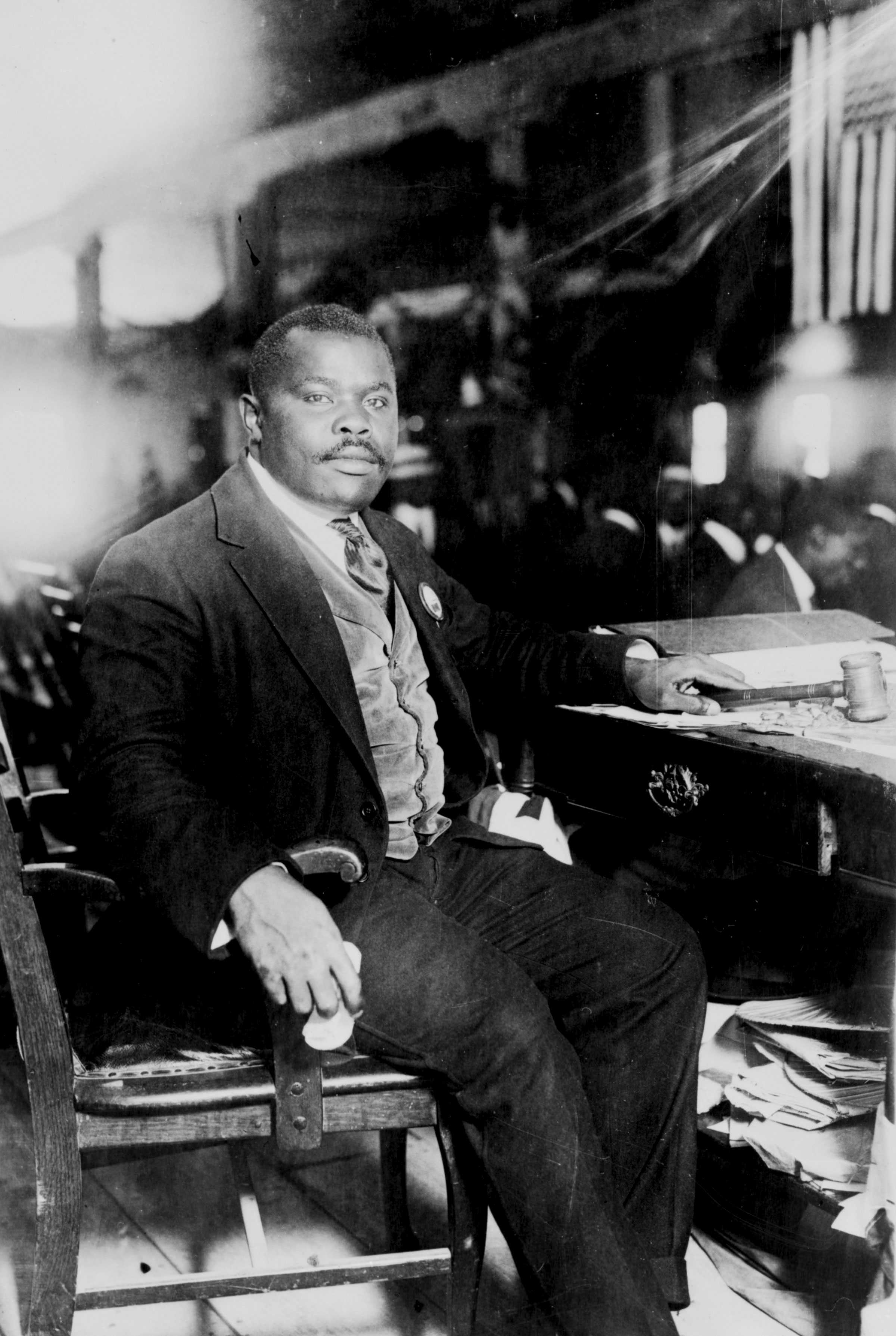 Black and white portrait of an African American man seated at a desk.  He has a moustache and short hair dressed in a suit and holds a gavel.