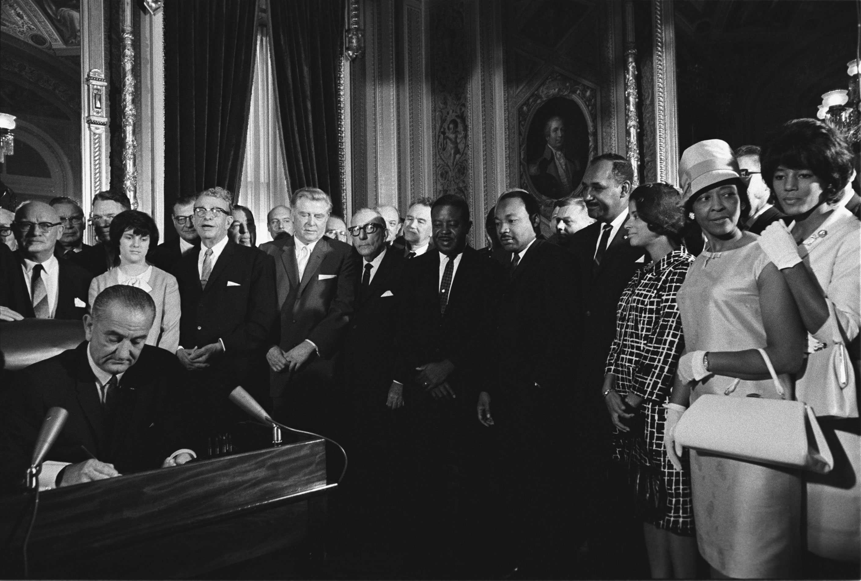 President Lyndon B. Johnson signing the Voting Rights Act around a large crowd of activists and politicians.