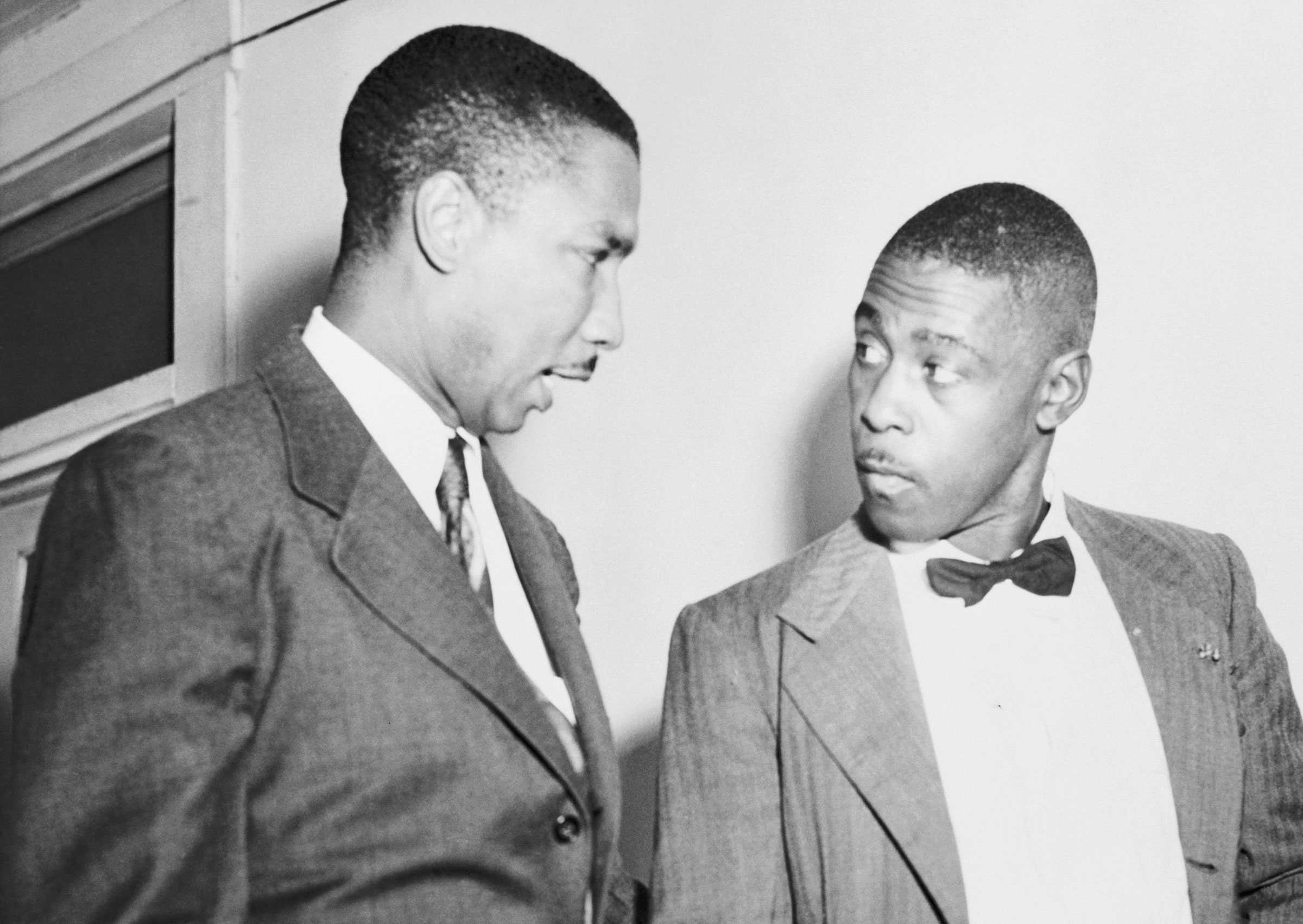 Mack Ingram and Robert H. Cartersuits stand in close conversation. The man on the left gestures while speaking; the man on the right listens intently.