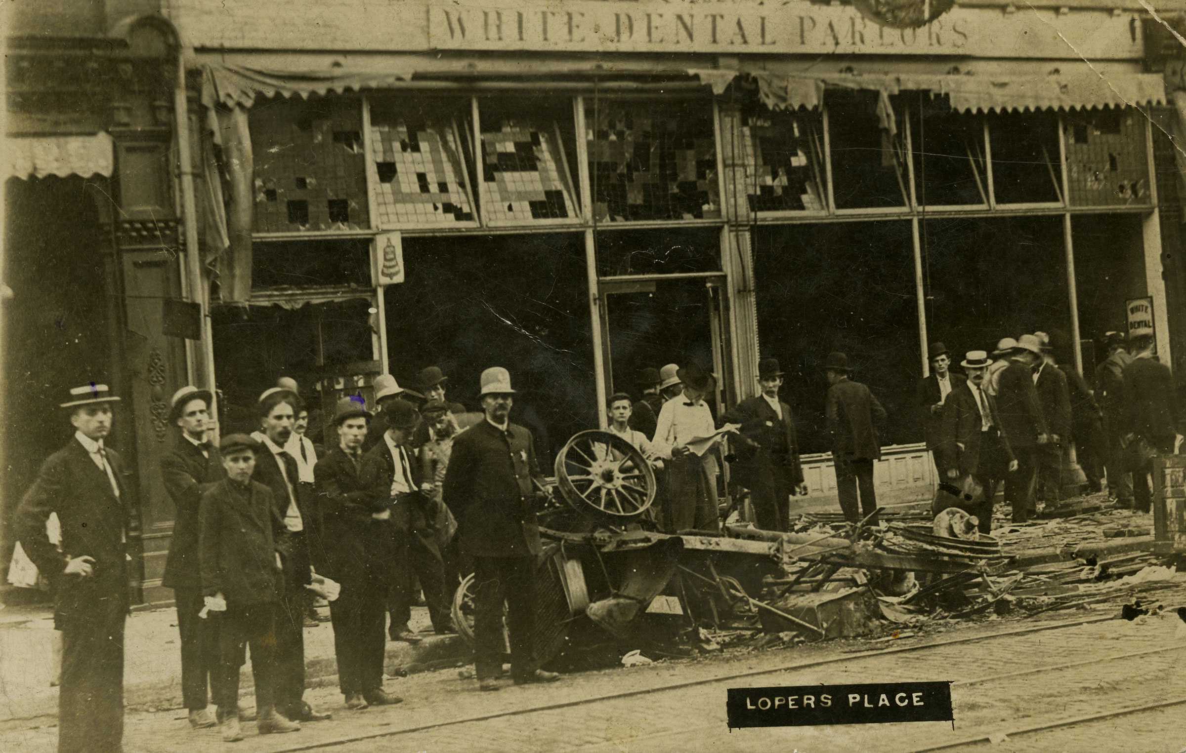 Black and white photograph showing the destruction of a city area.  There are people in surveying the destruction.