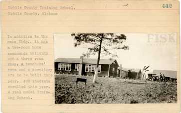 Historic photo of Mobile County Training School building with tree and vehicles in foreground.