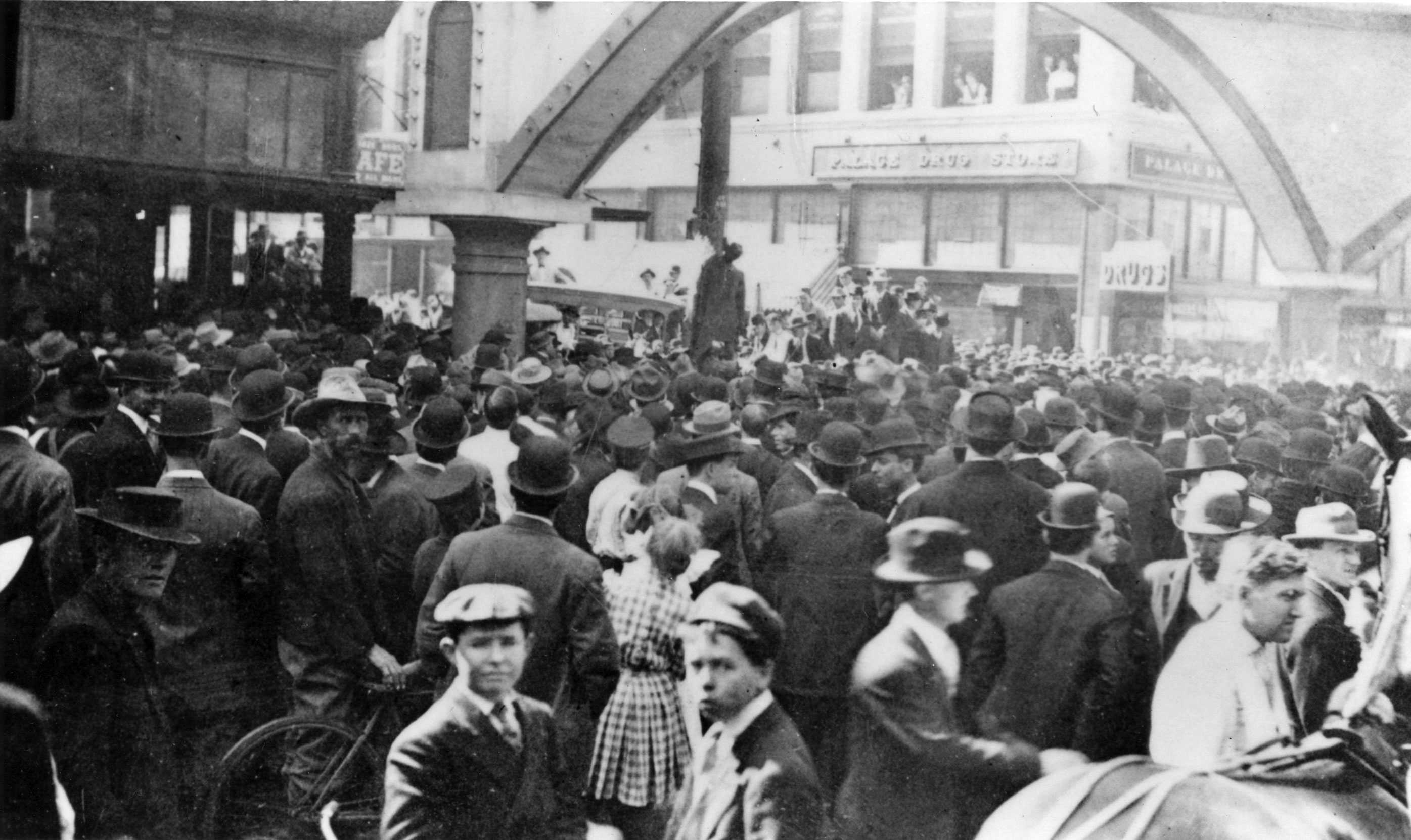 Black and white photograph of the lynching of Allen Brooks taken from elevated perspective. A large crowd around his body.