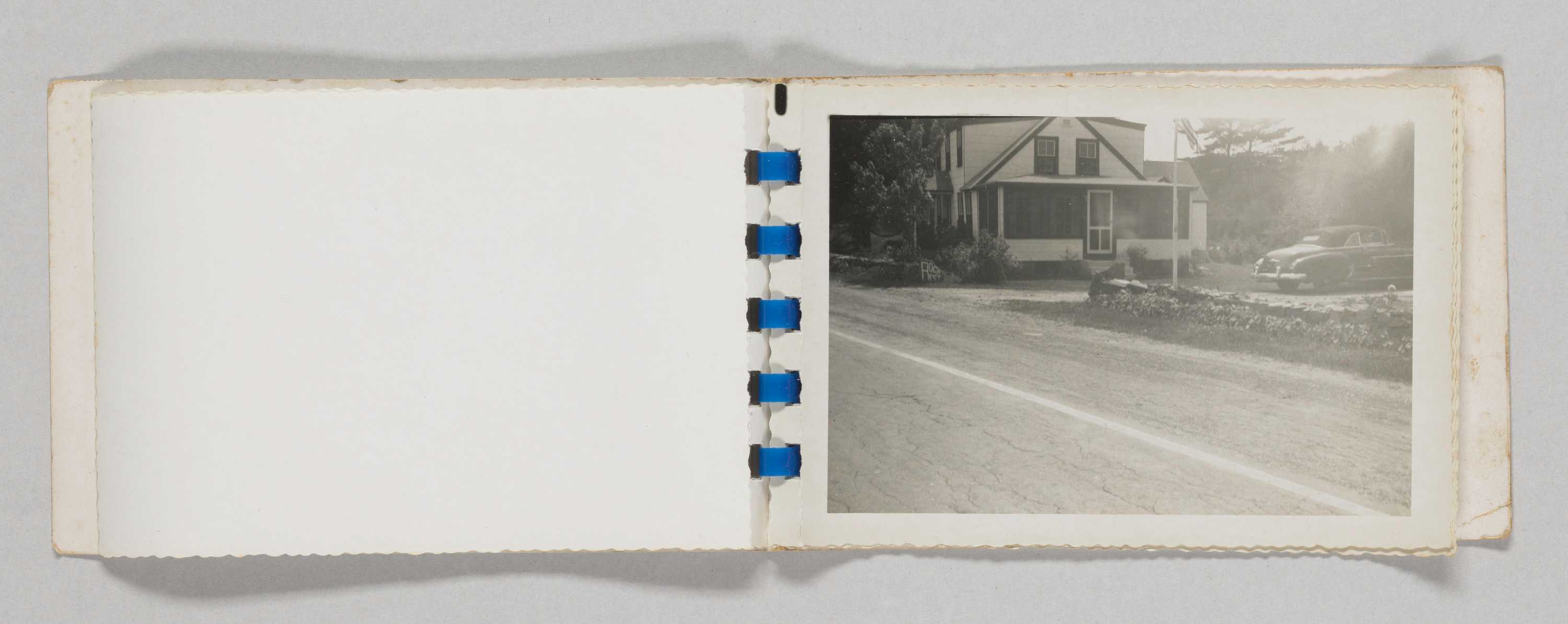 Photographic album opened to a page showing a house with a porch