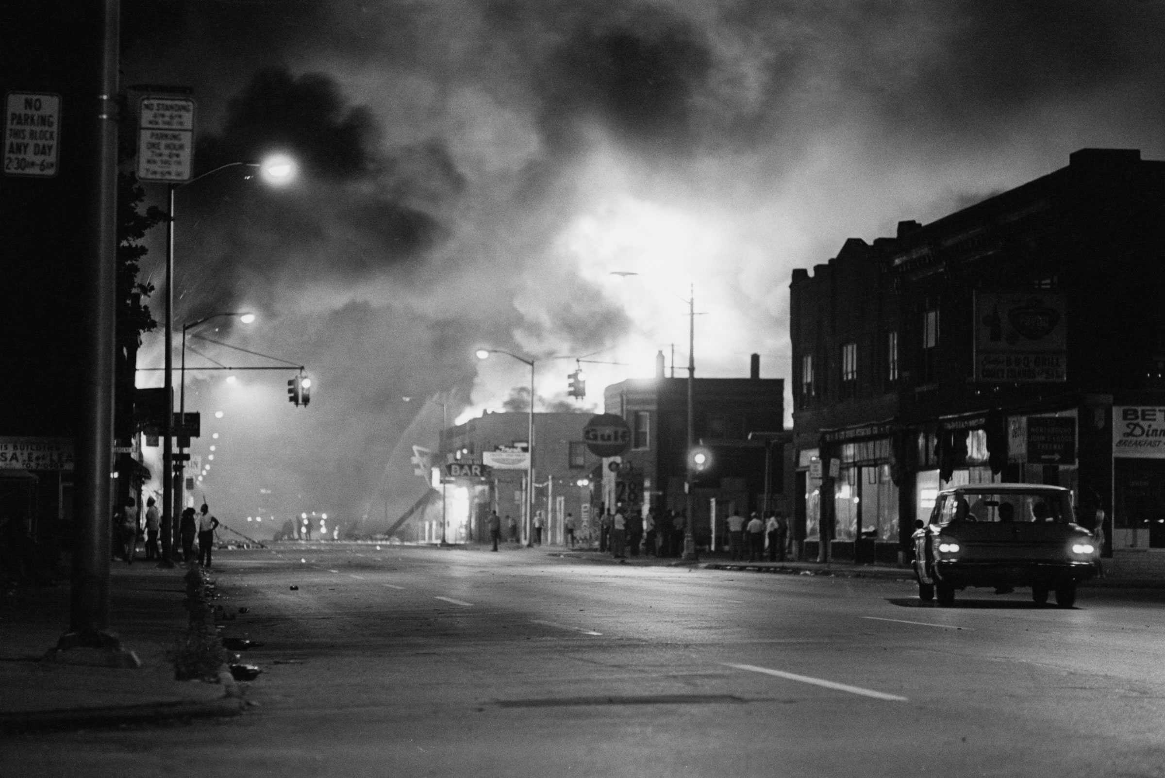 A black and white photograph of an almost empty street in Detroit's west side after rioters loot and burn an after-hours club.