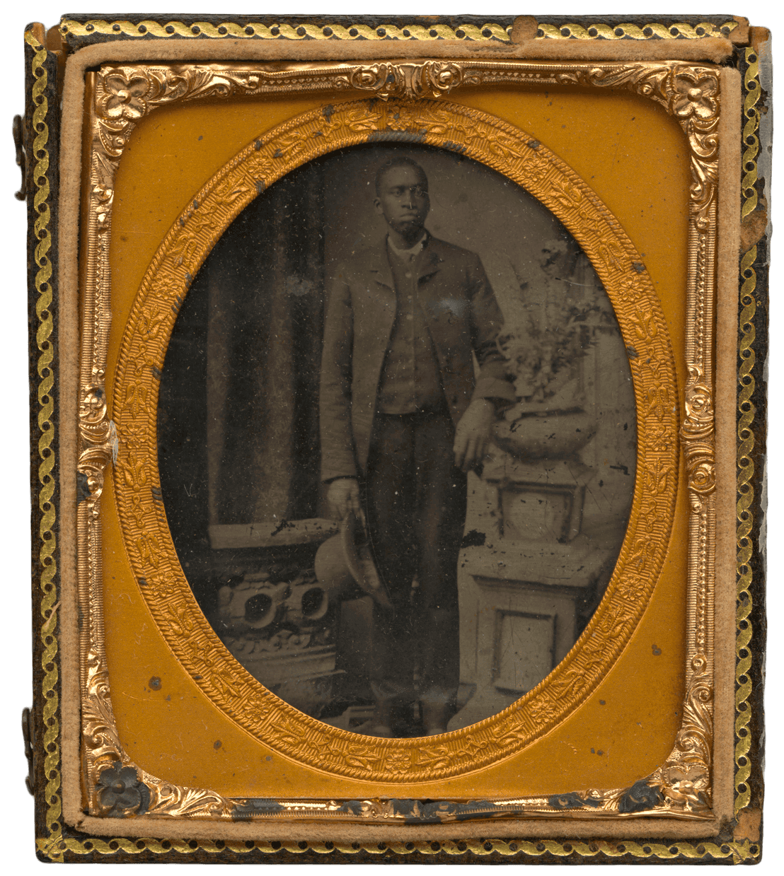 Tintype of a man in a suit. The tintype is housed in a case with decorative gold metal oval frame.