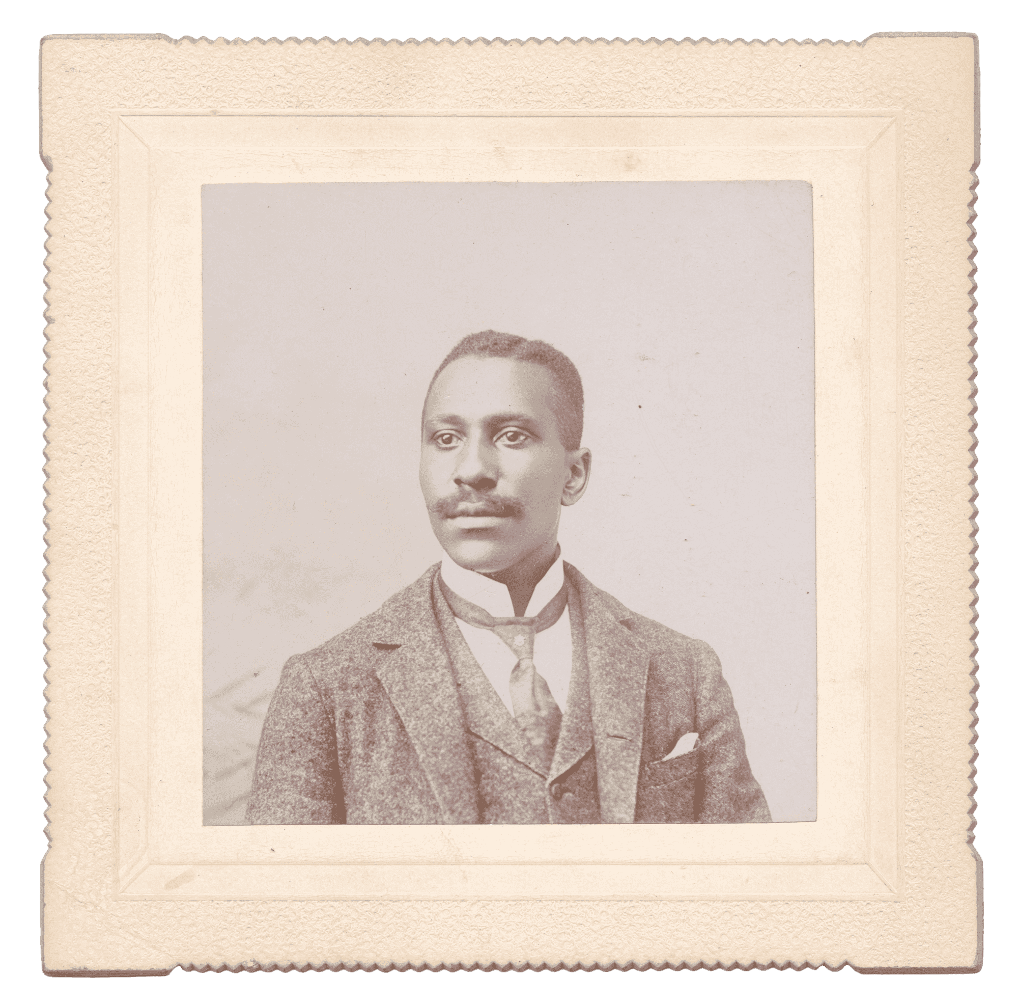 A portrait of an unidentified man in a marled suit, tie with a flower pin, and a mustache on a square card mount.