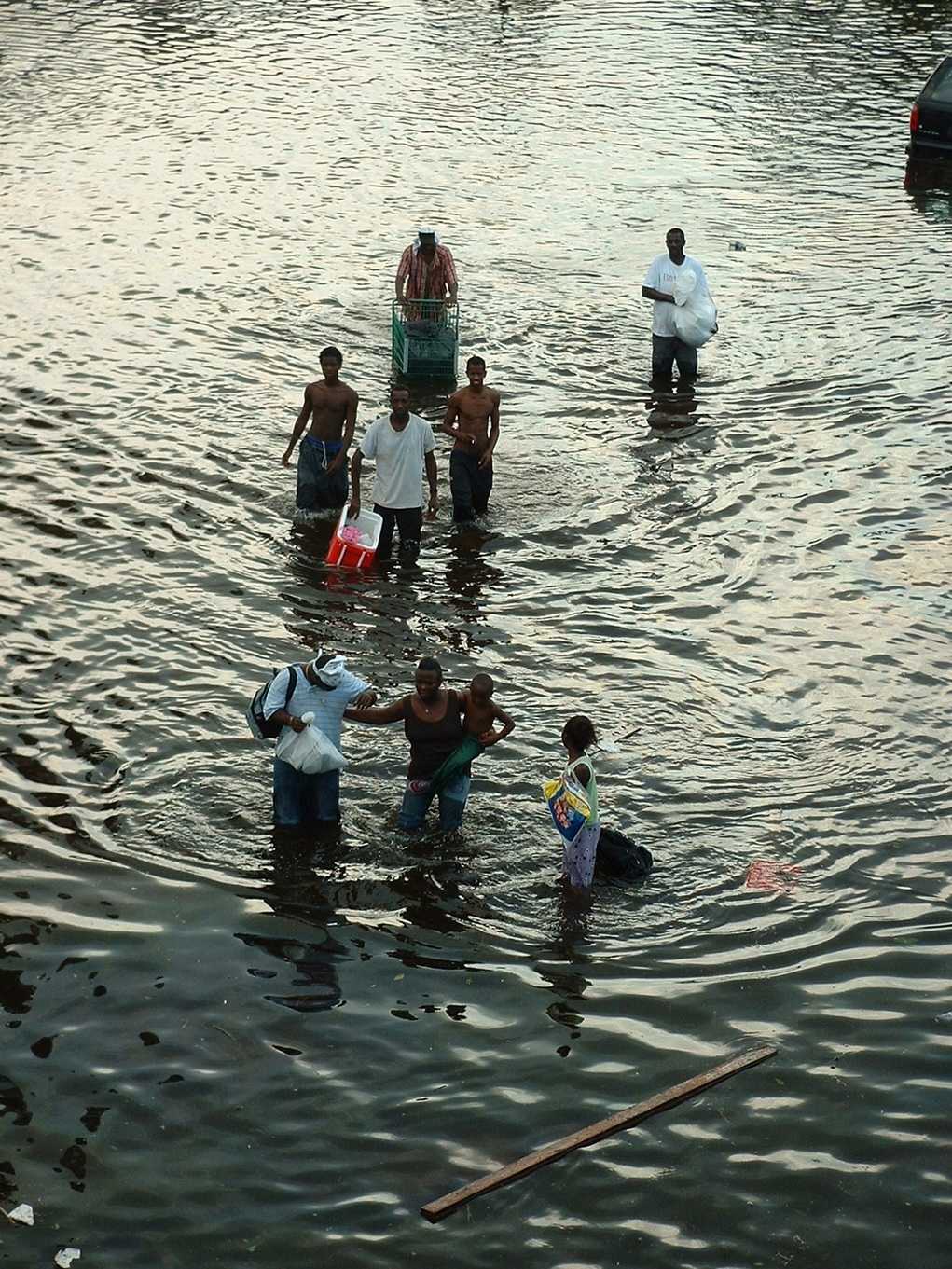 Color photograph of people walking through flood waters during Hurricane Katrina.