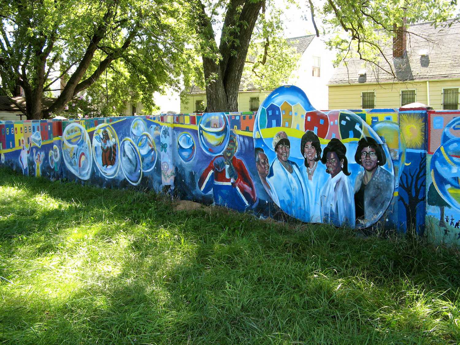 Color photograph of a concrete wall covered in murals.