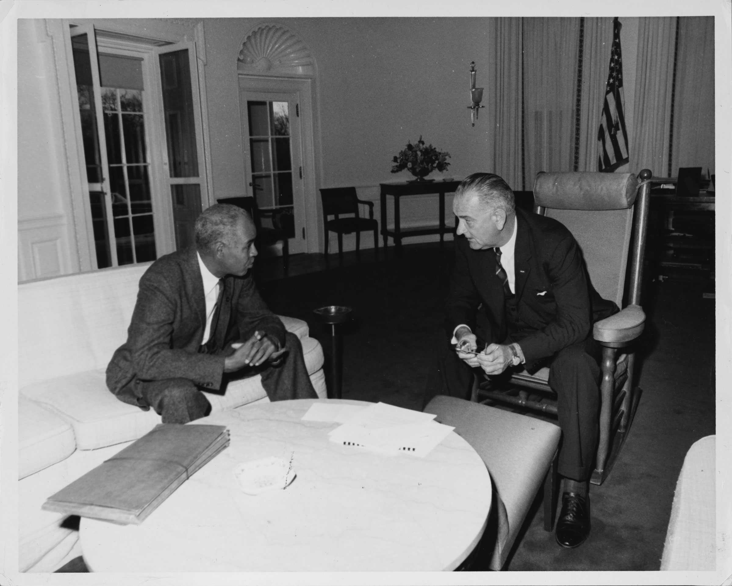 A black and white photograph of Roy Wilkins and President Lyndon B. Johnson sitting and discussing the he Voting Rights Act of 1965 in the White House.