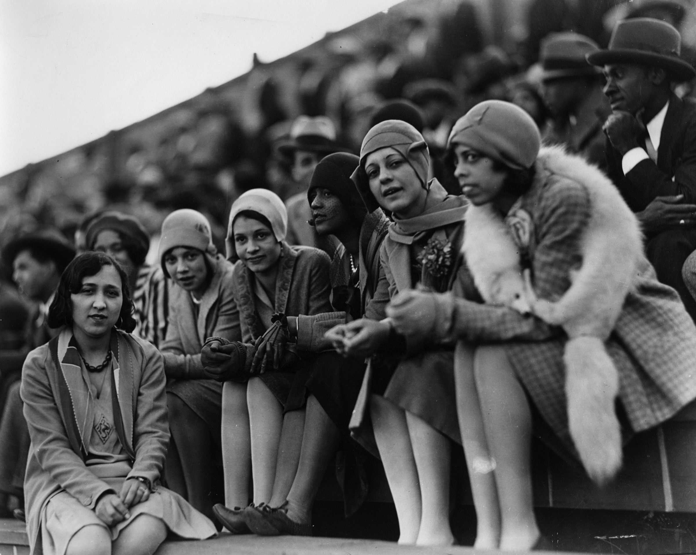 Black and white photograph of young African American women seated on a bench in a stadium.