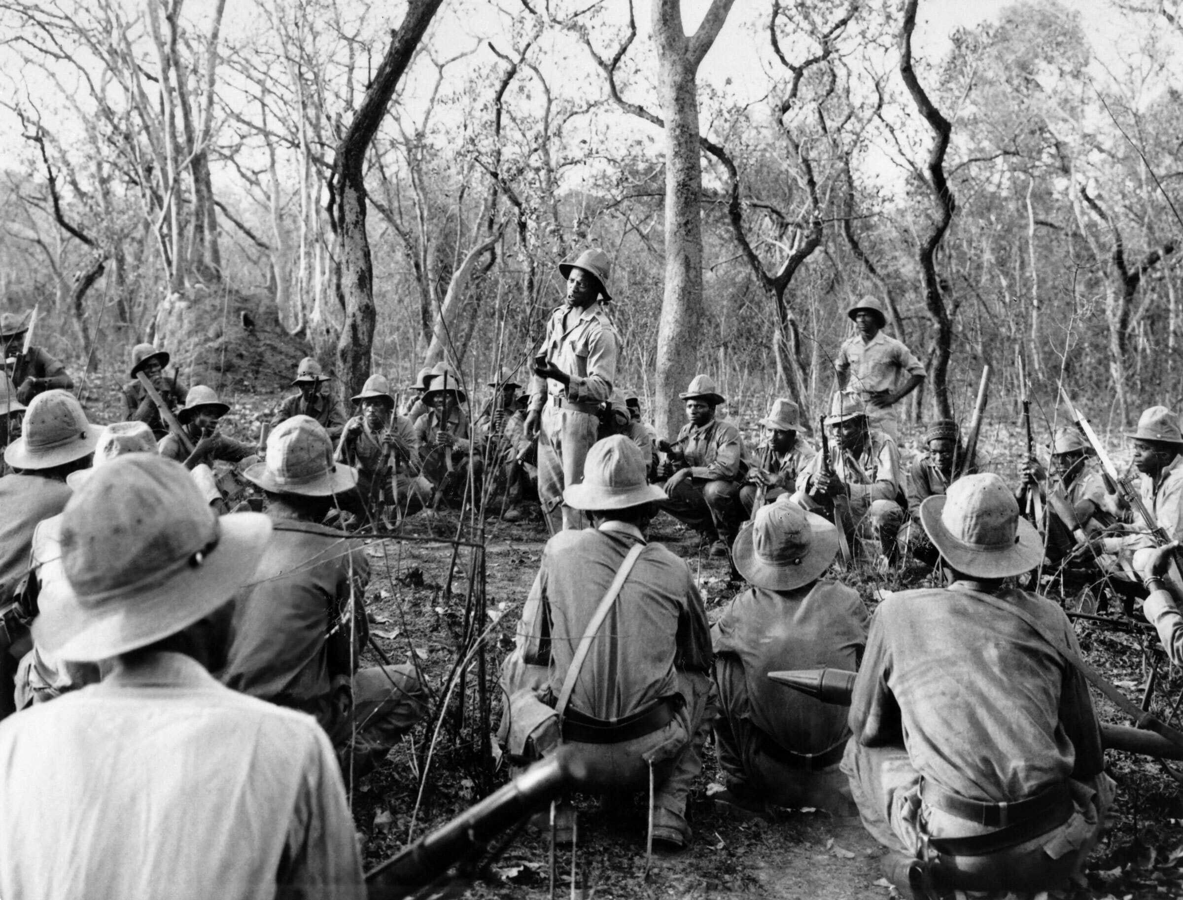 Black and white photograph of fighters of African Party for the Independence of Guinea and Cape Verde in a woods.