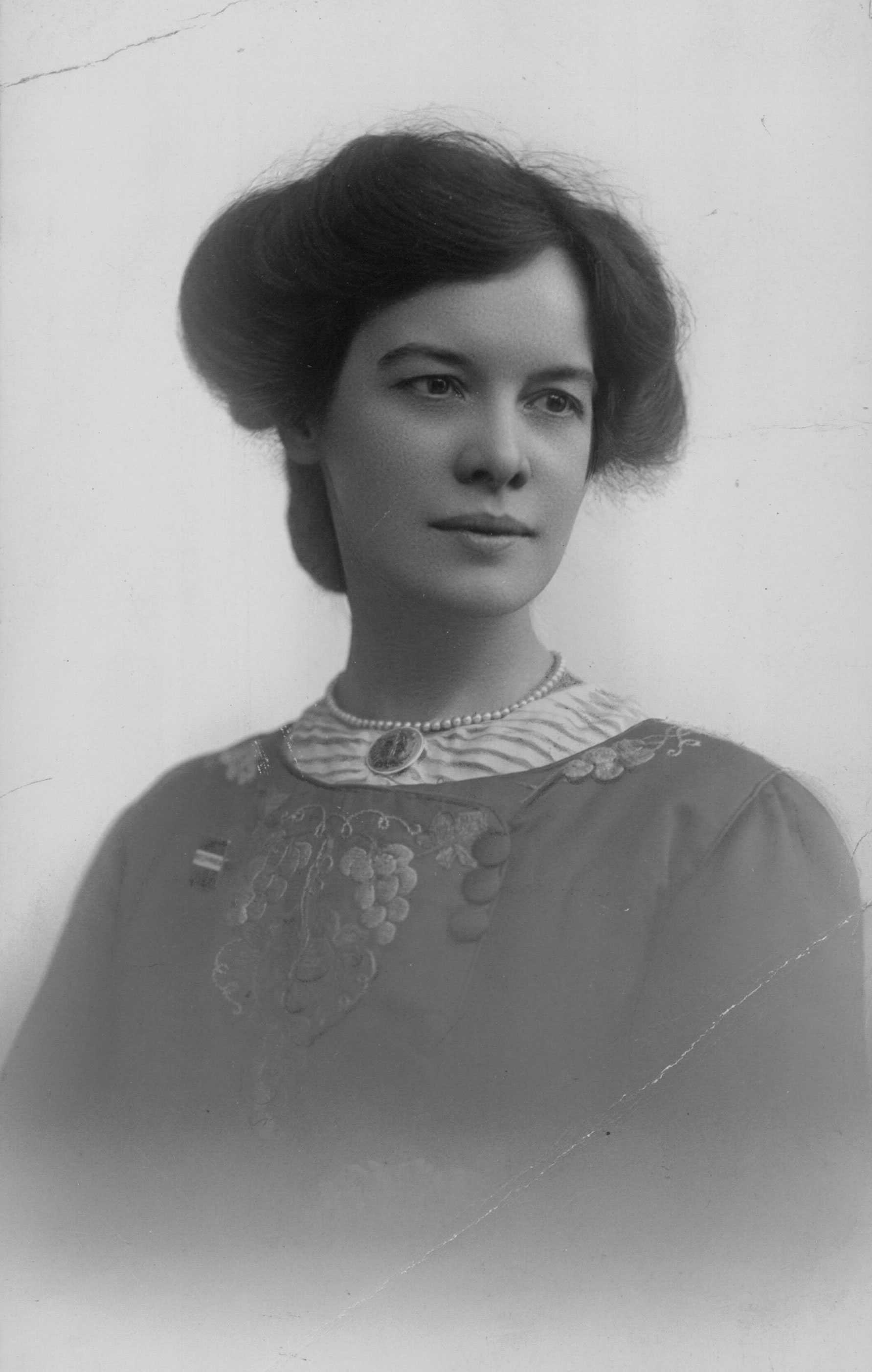 Half-length portrait of a woman wearing a decorative dress and pearls.