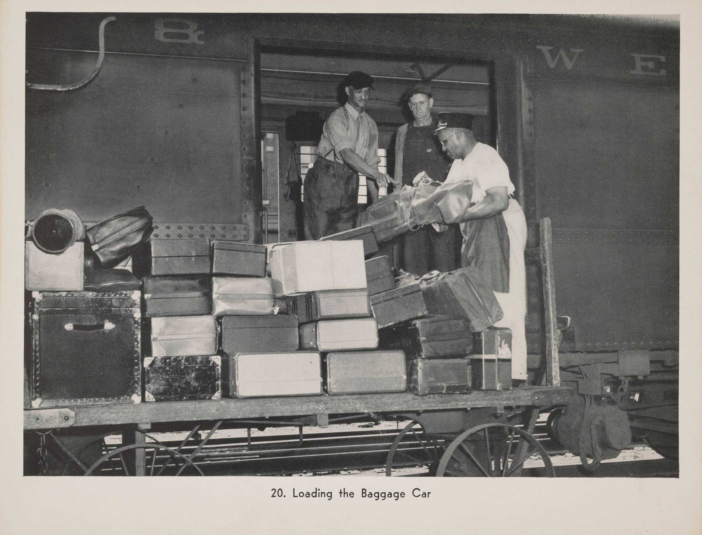 A black and white photograph of three men loading baggage on to a train car.