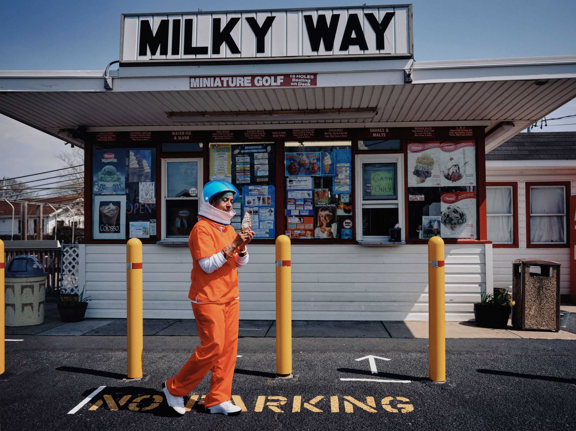 An escaped astronuat prisioner eating soft served ice cream from a small ice cream stand called the Milky Way.