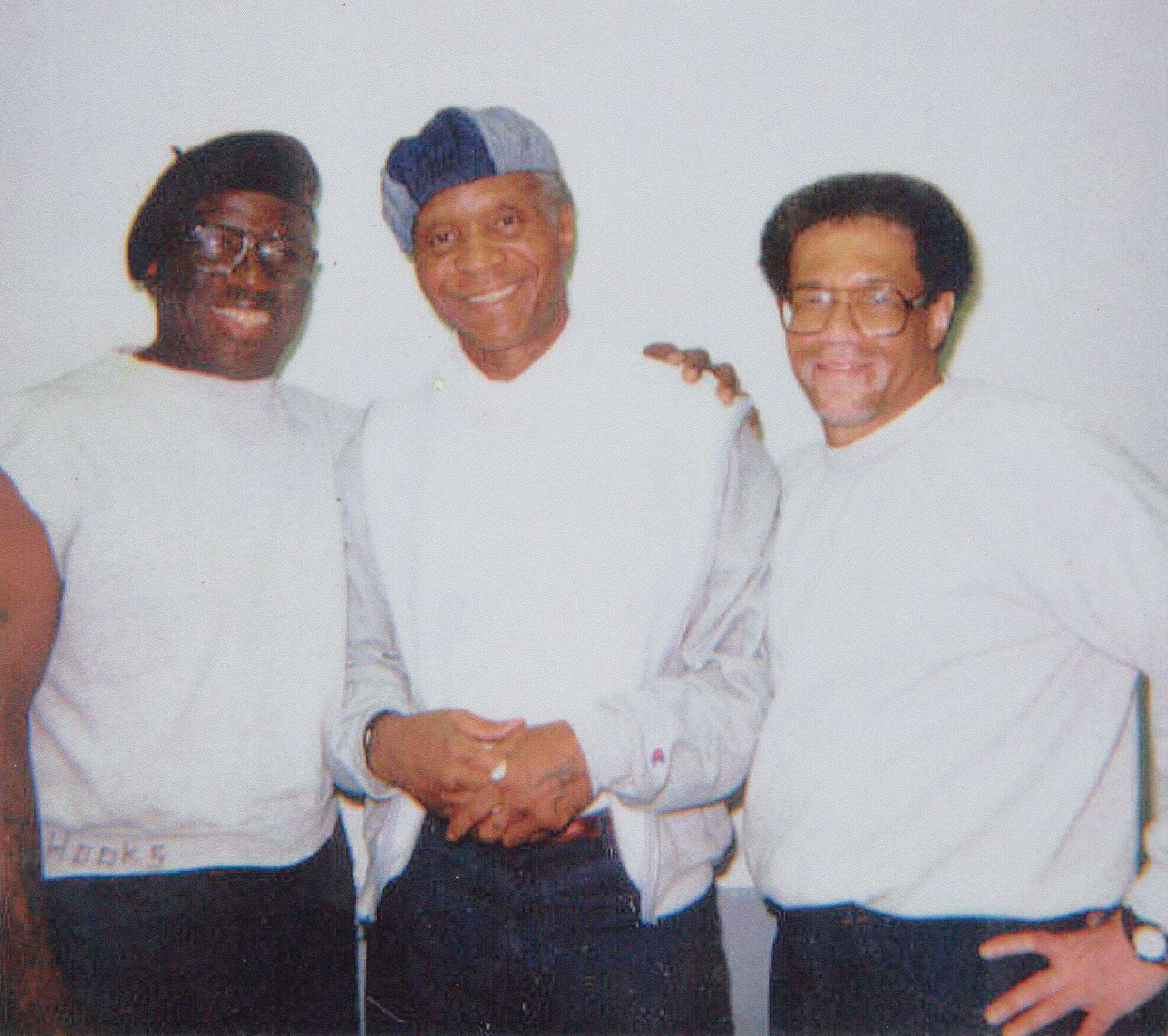 A photo of Herman Wallace, Robert King, and Albert Woodfox standing with each other, smiling, looking at the camera.