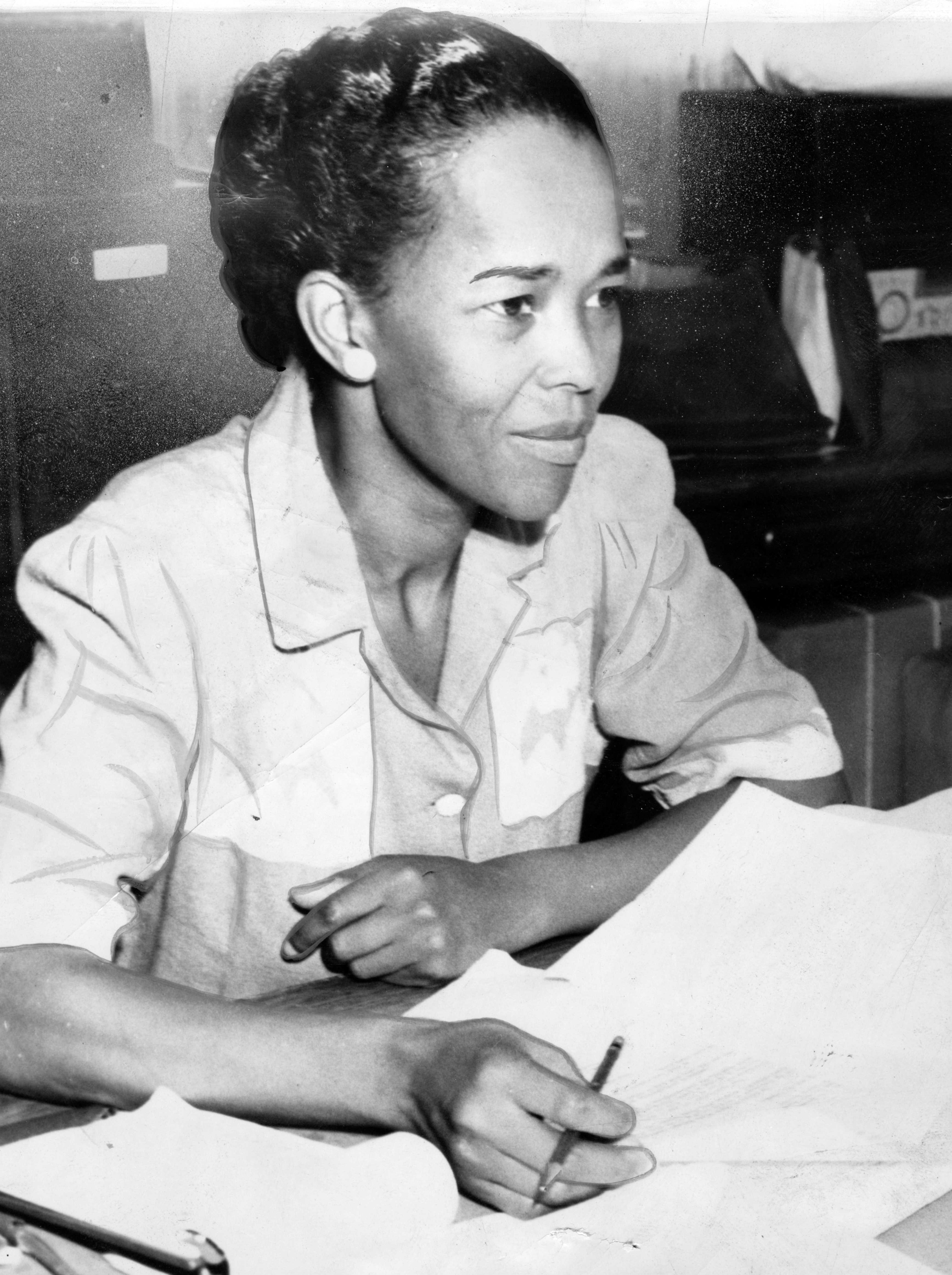 Black and white photograph of Ella Baker seated with a pencil and papers laid out before her.